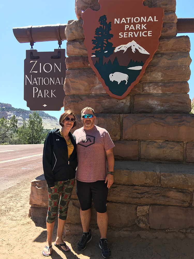 Visitors at Zion National Park entrance sign in Springdale Utah