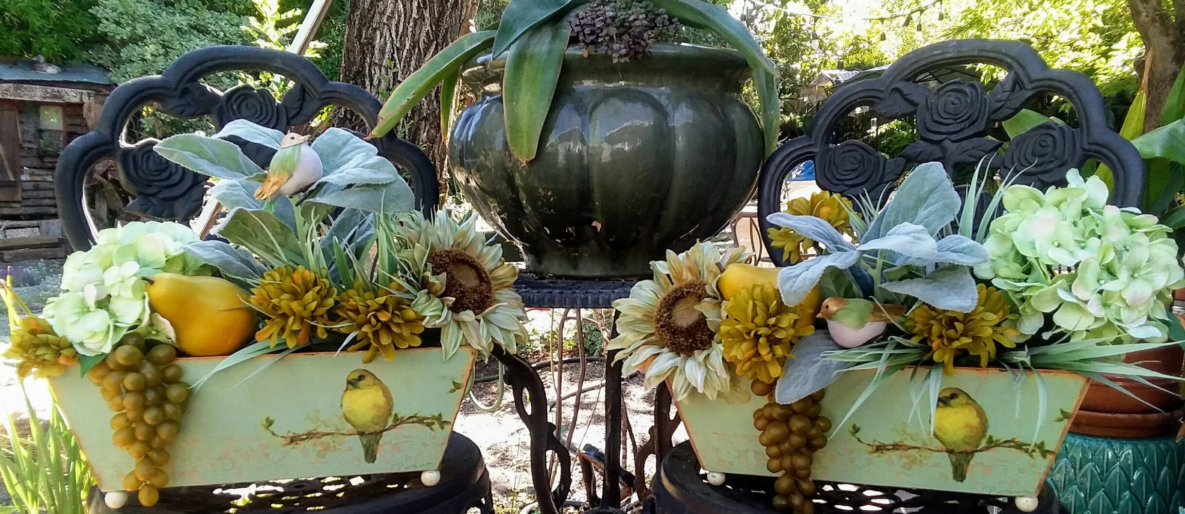 These two arrangements were assembled to be displayed up high, above kitchen cabinets. The colors of the bird decals on the containers were repeated in the pears, grapes, the golden chrysanthemums and the centers of the sunflowers. The mint background of the containers is repeated in the hydrangeas and the petals of the sunflowers as well as the mint-colored grassy foliage.