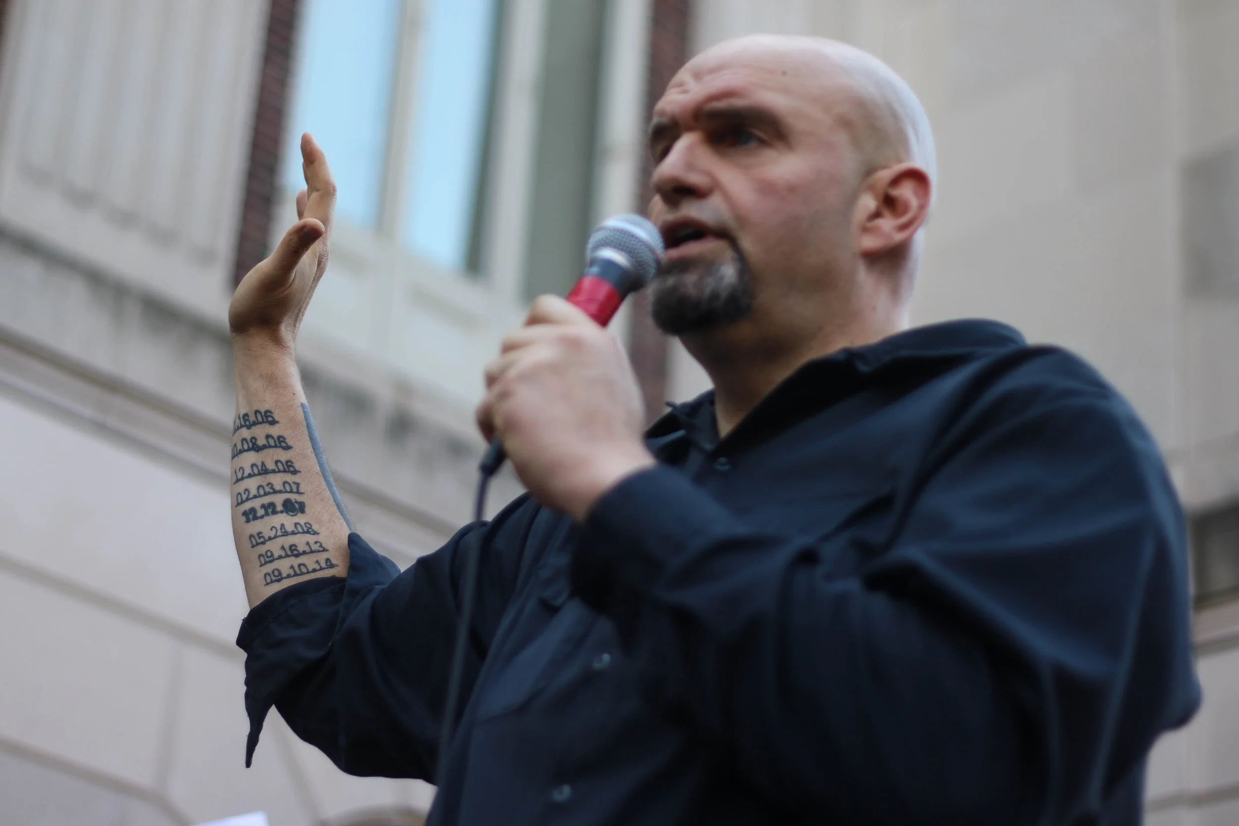  U.S. Sen. John Fetterman displays a row of tattoos commemorating homicide victims in Braddock, Pennsylvania during a rally for gun control in 2018. (For WHYY) 