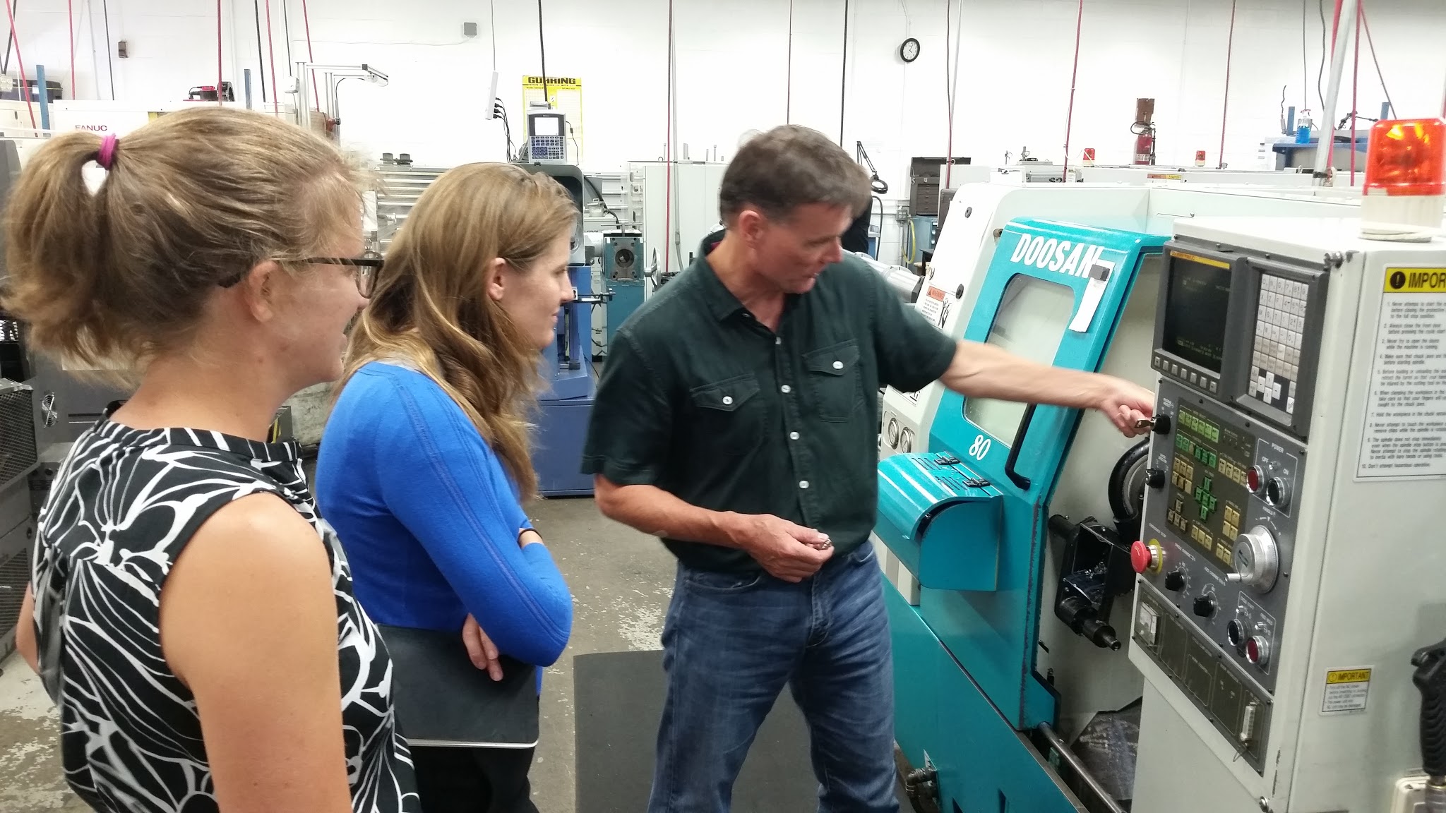 CIC Staffers Shellie Cohen (left) and Julia Hansen (center) watch CCG's Mark Flannigan (right) demonstrate on a milling machine.