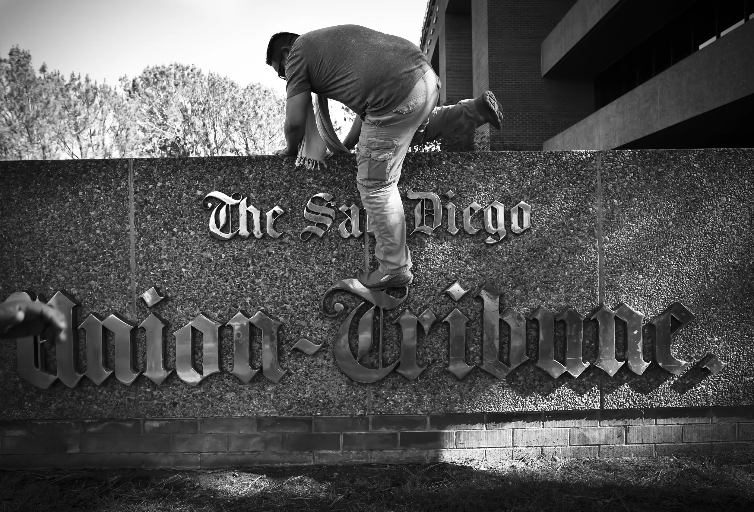 After 43 years in the same location, The San Diego Union-Tribune newspaper moves from its building in Mission Valley to new offices in downtown San Diego. Here photographer Alejandro Tamayo climbs down from the sign in front of the building shortly after the photography staff took a going-away group photo there.