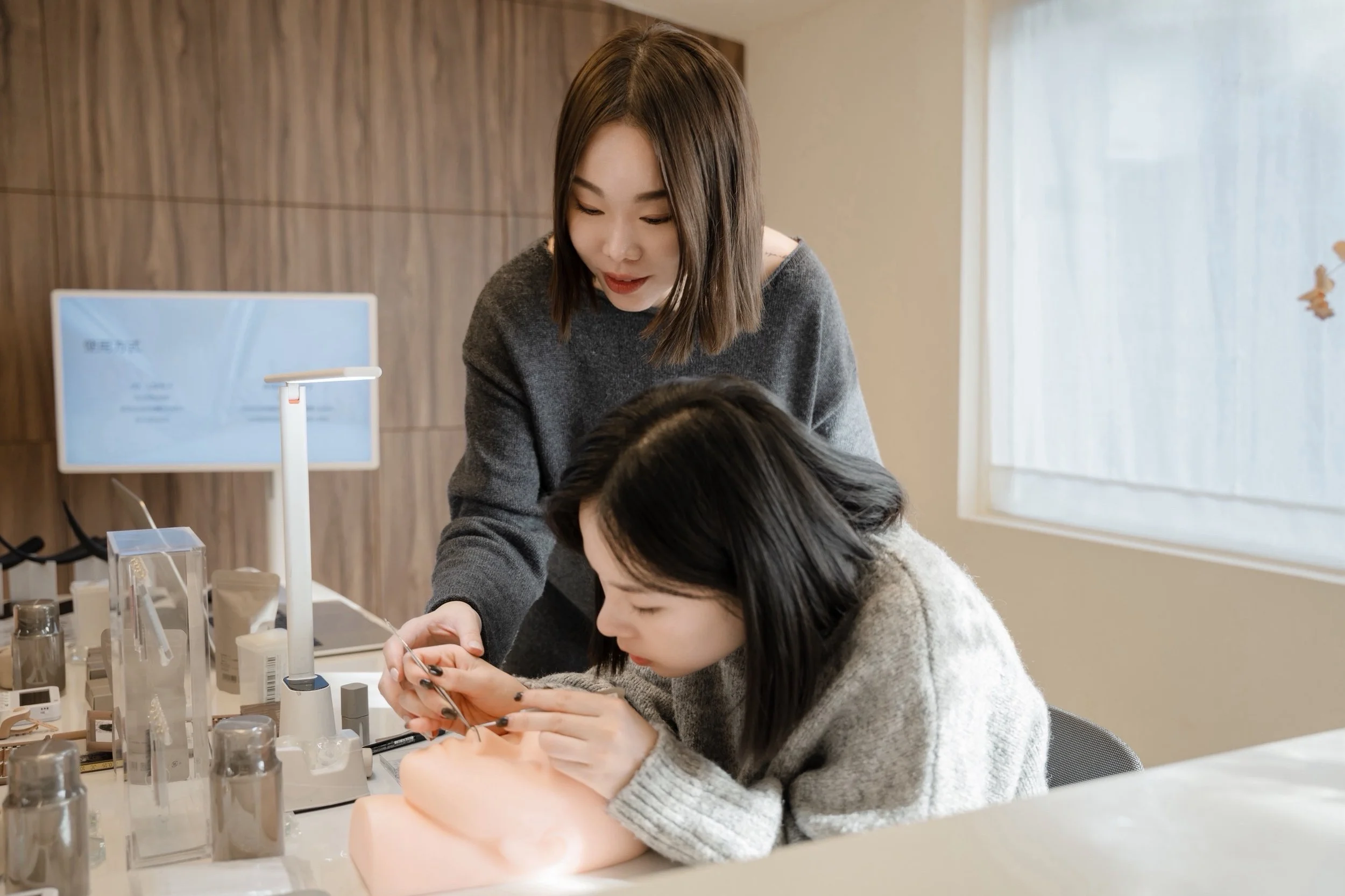 Two women practicing dental procedures on a mannequin in a clinical setting.