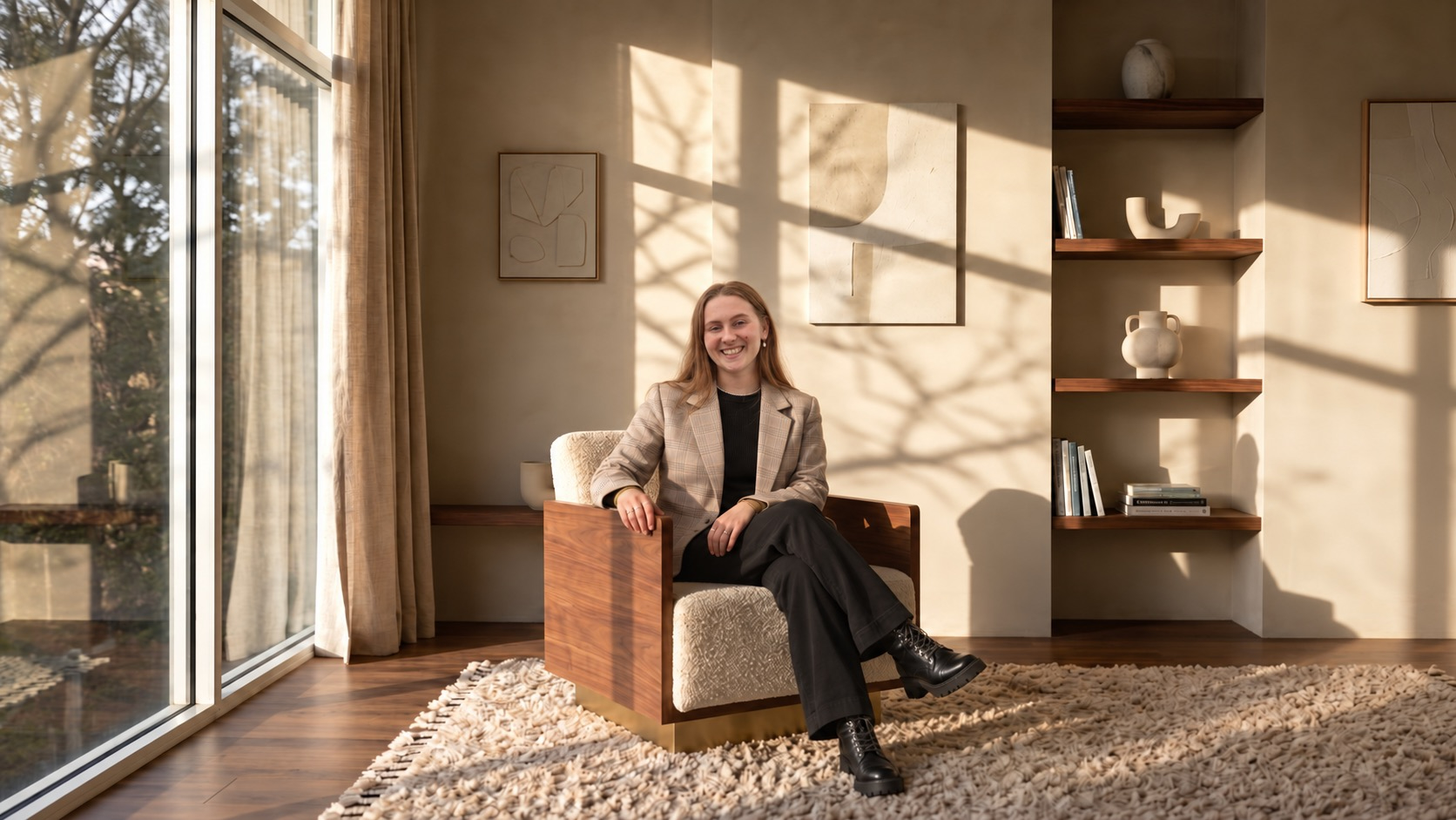 Smiling psychologist businesswoman in a plaid blazer sitting in a modern office lounge with warm, natural sunlight.