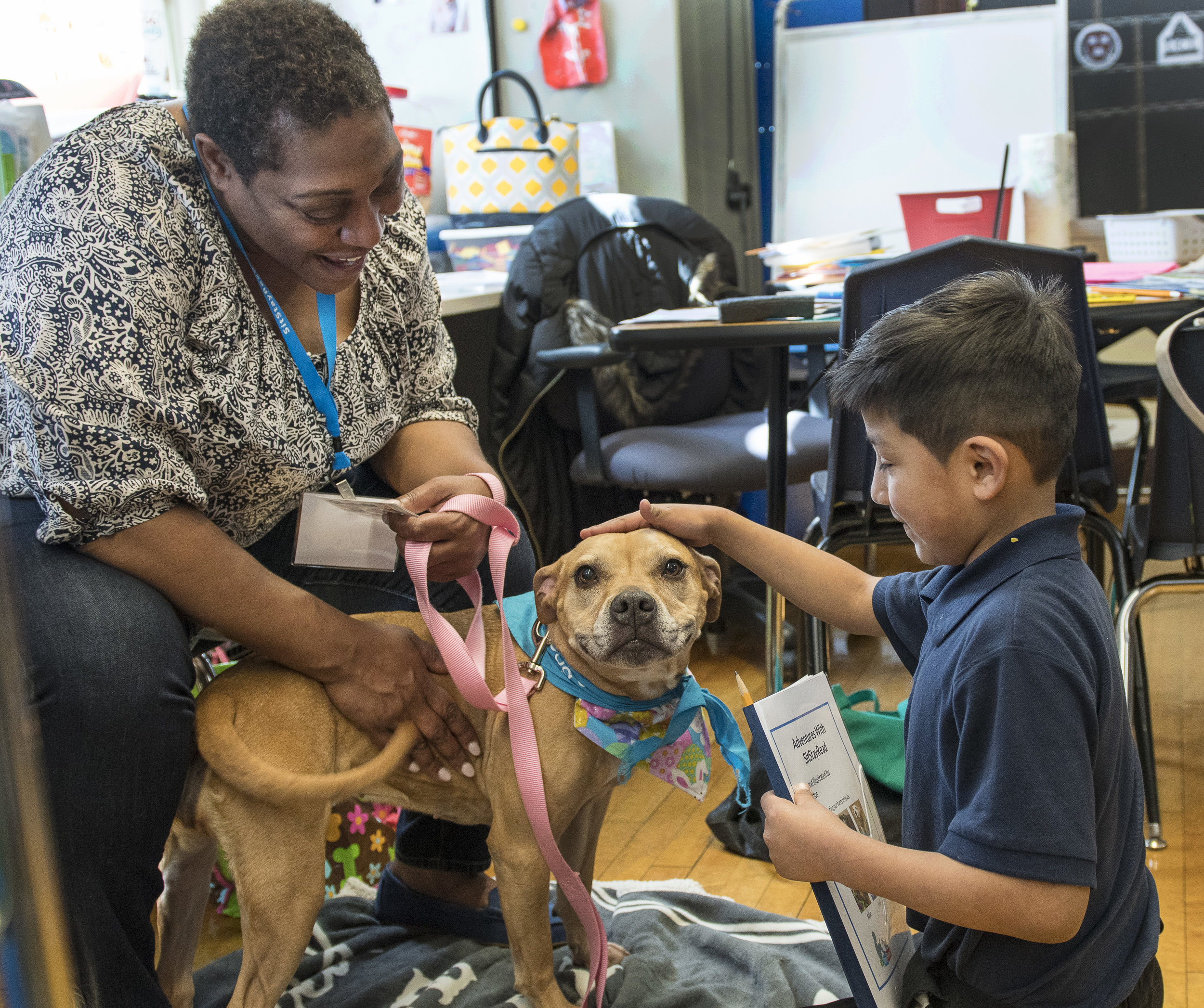 Dog Team volunteer Lisa and her Certified Reading Assistance Dog Allie listen to a second grade student in the SitStayRead Tail Blazers program at Marquette Elementary. (J. Sall)