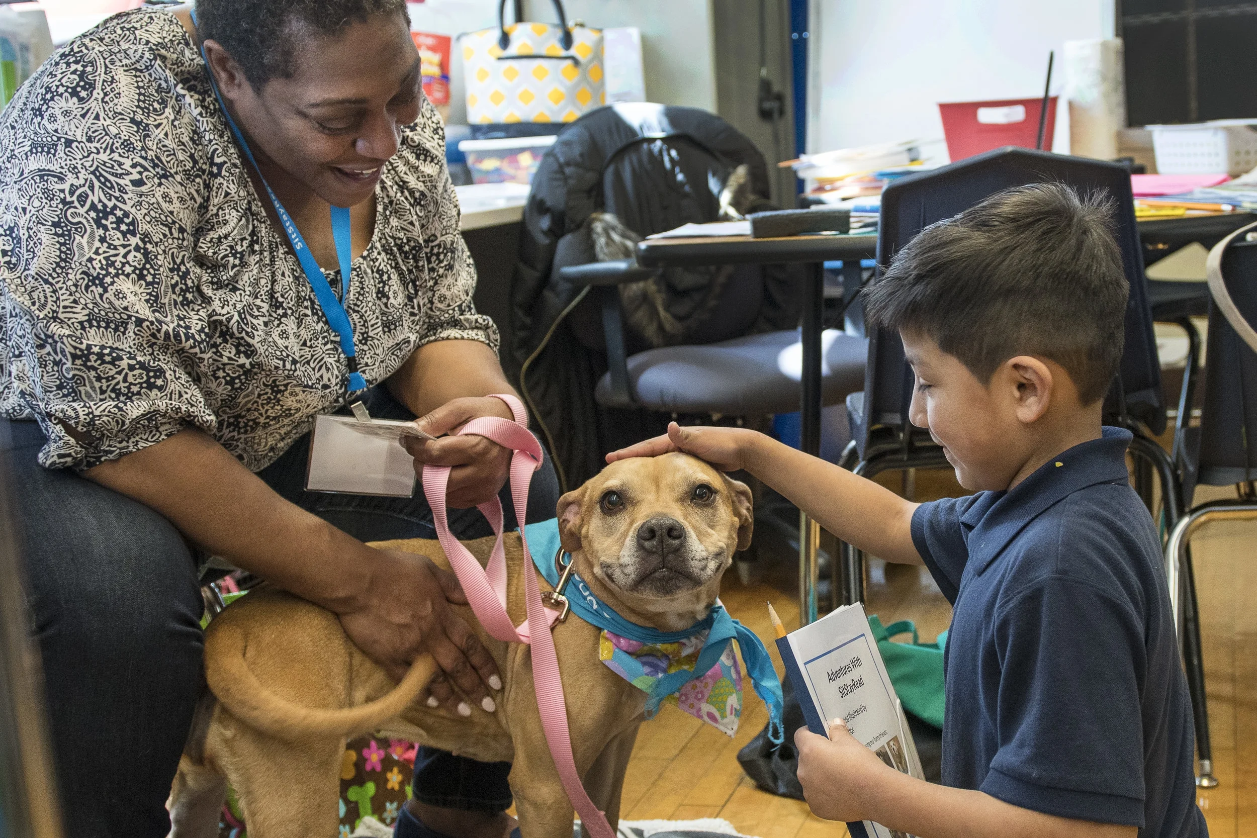 Dog Team volunteer Ms. Lisa and her Certified Reading Assistance Dog Allie listen to second-grade student Inez read one of her stories out loud. (J. Sall)