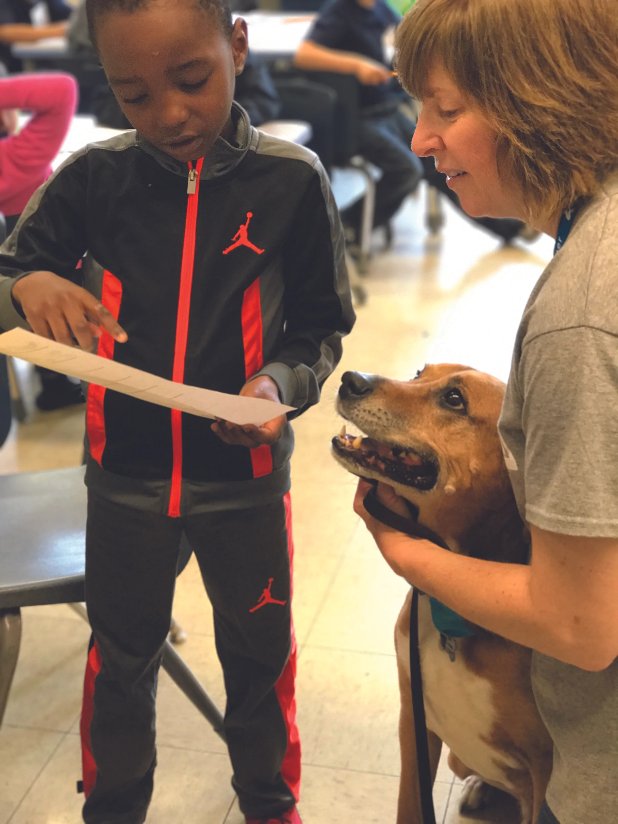 Certified Reading Assistance Dog Buster listens to a first-grade student's story in a Little Buddies program. (K. Love)