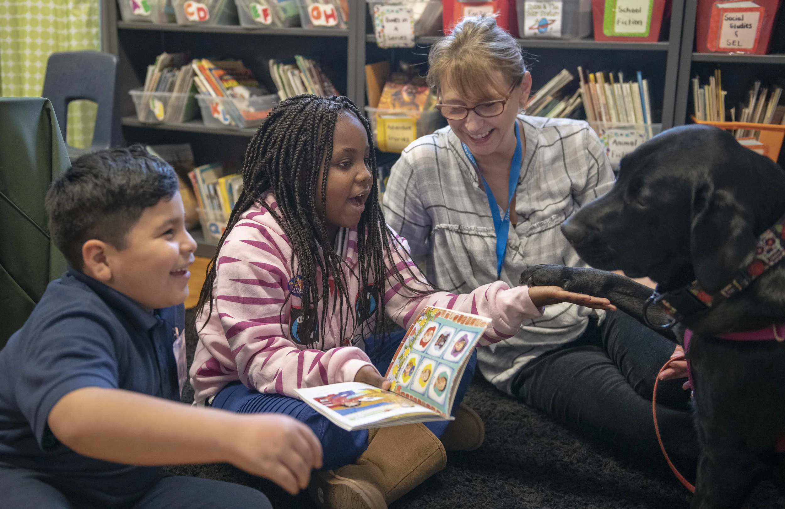 Dog Team volunteer Lisa Sall with her Certified Reading Assistance Dog Jinks reading with students in a Tail Blazers program at Marquette Elementary. (J. Sall)