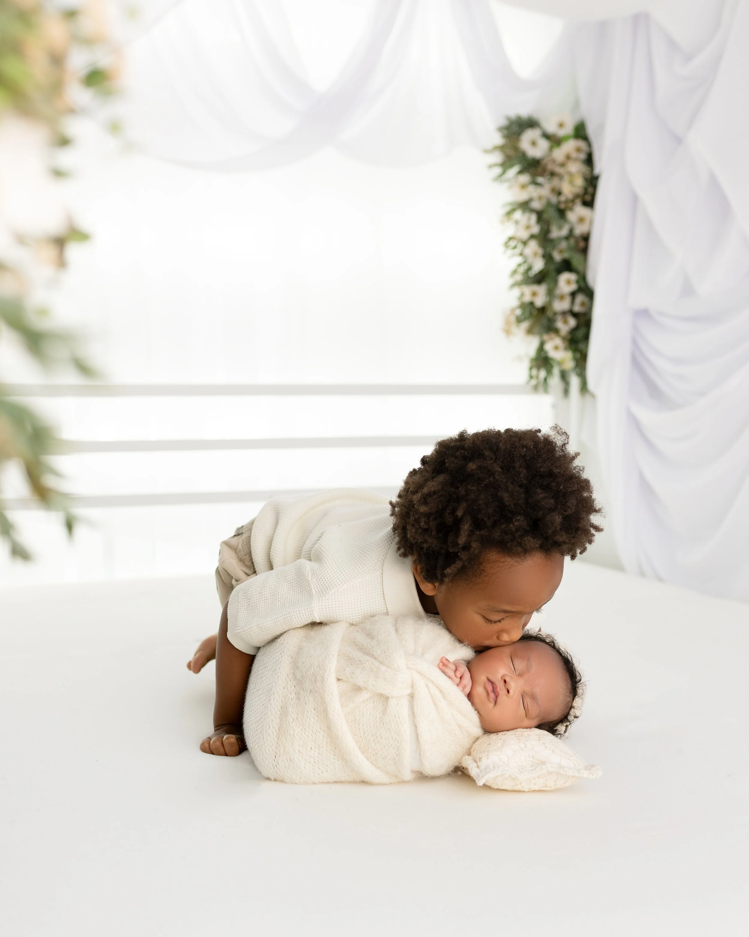 Brother and newborn baby on bed