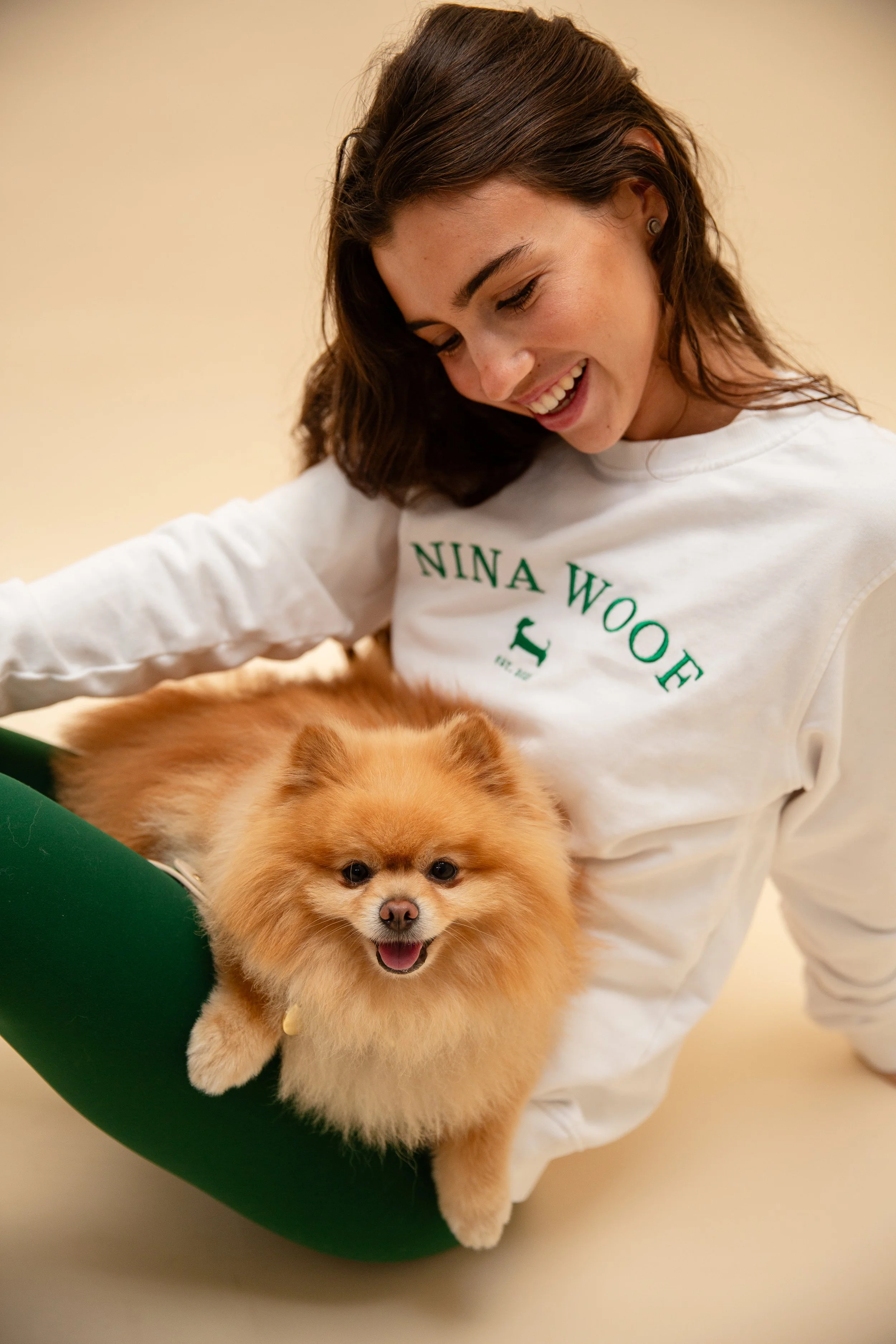 Pomeranian dog posing with model who is wearing a Nina Woof jumper
