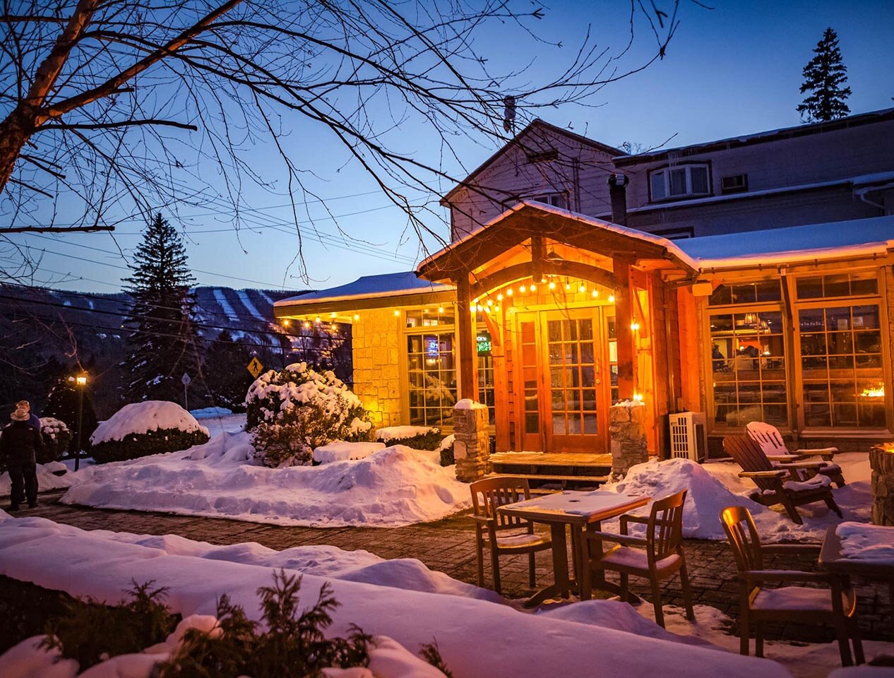 The exterior of the Clubhouse at Windham Mountain, dusted with show and lit up for the evening.