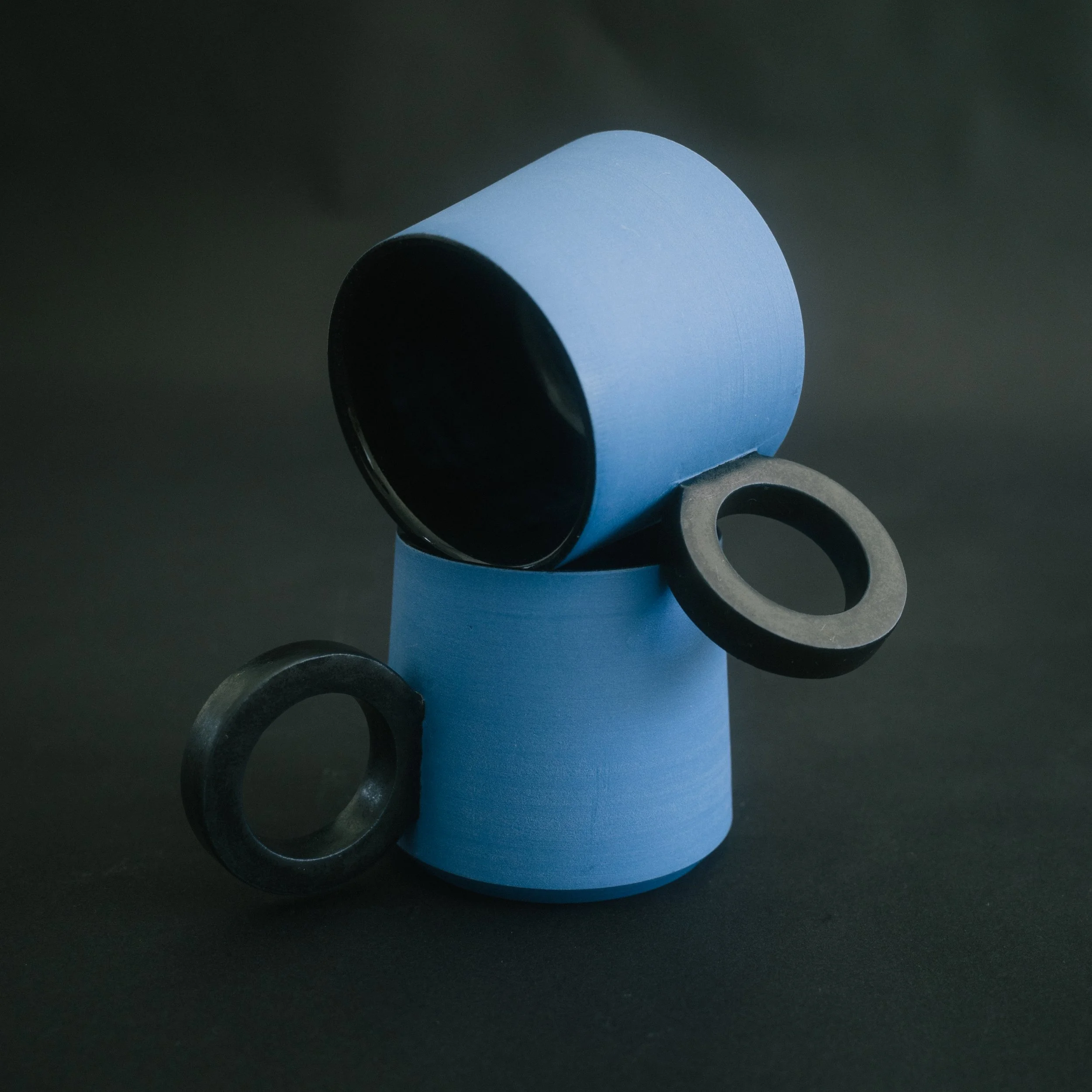 2 blue ceramic espresso cups with black handles on a black seamless background.
