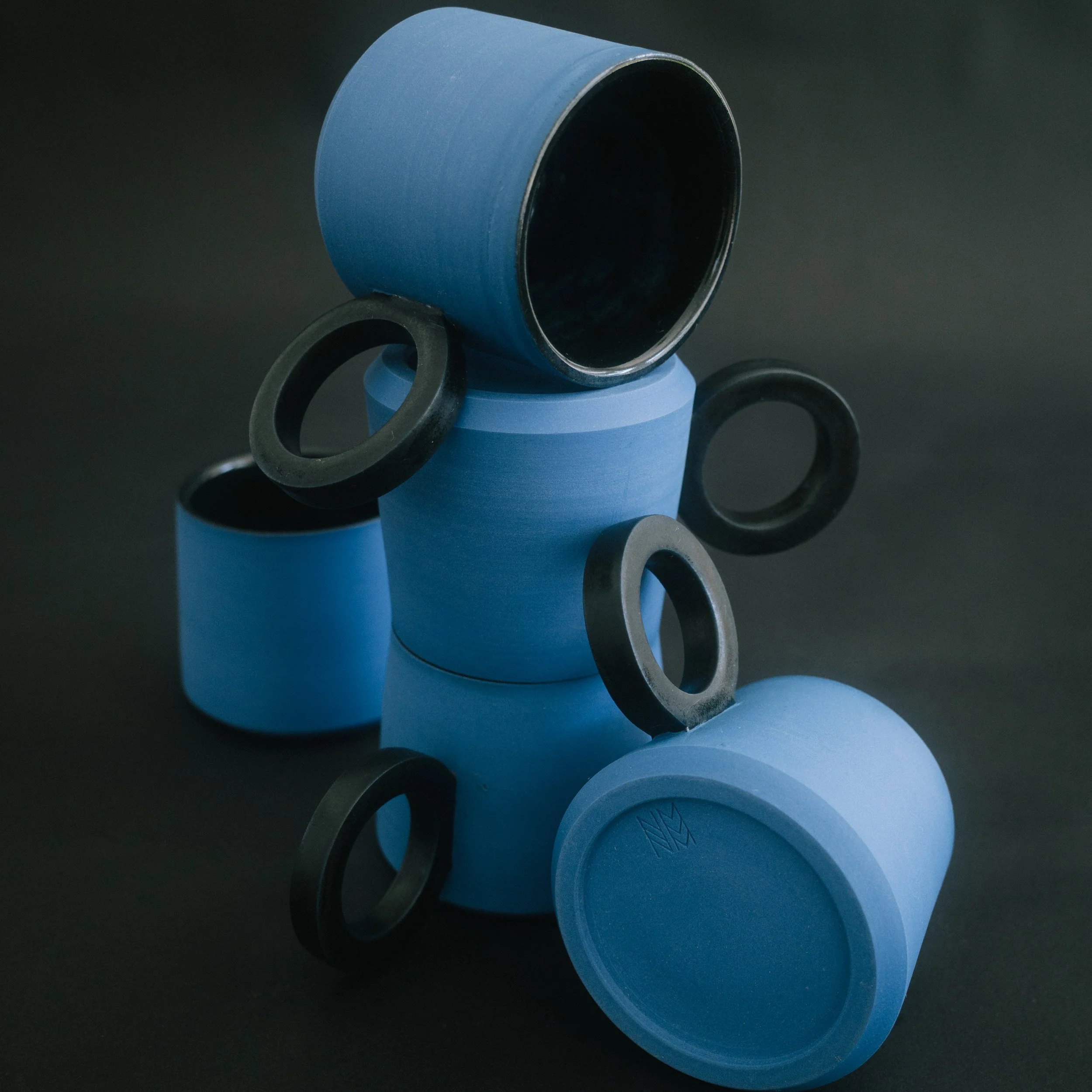 2 blue ceramic espresso cups with black handles on a black seamless background.