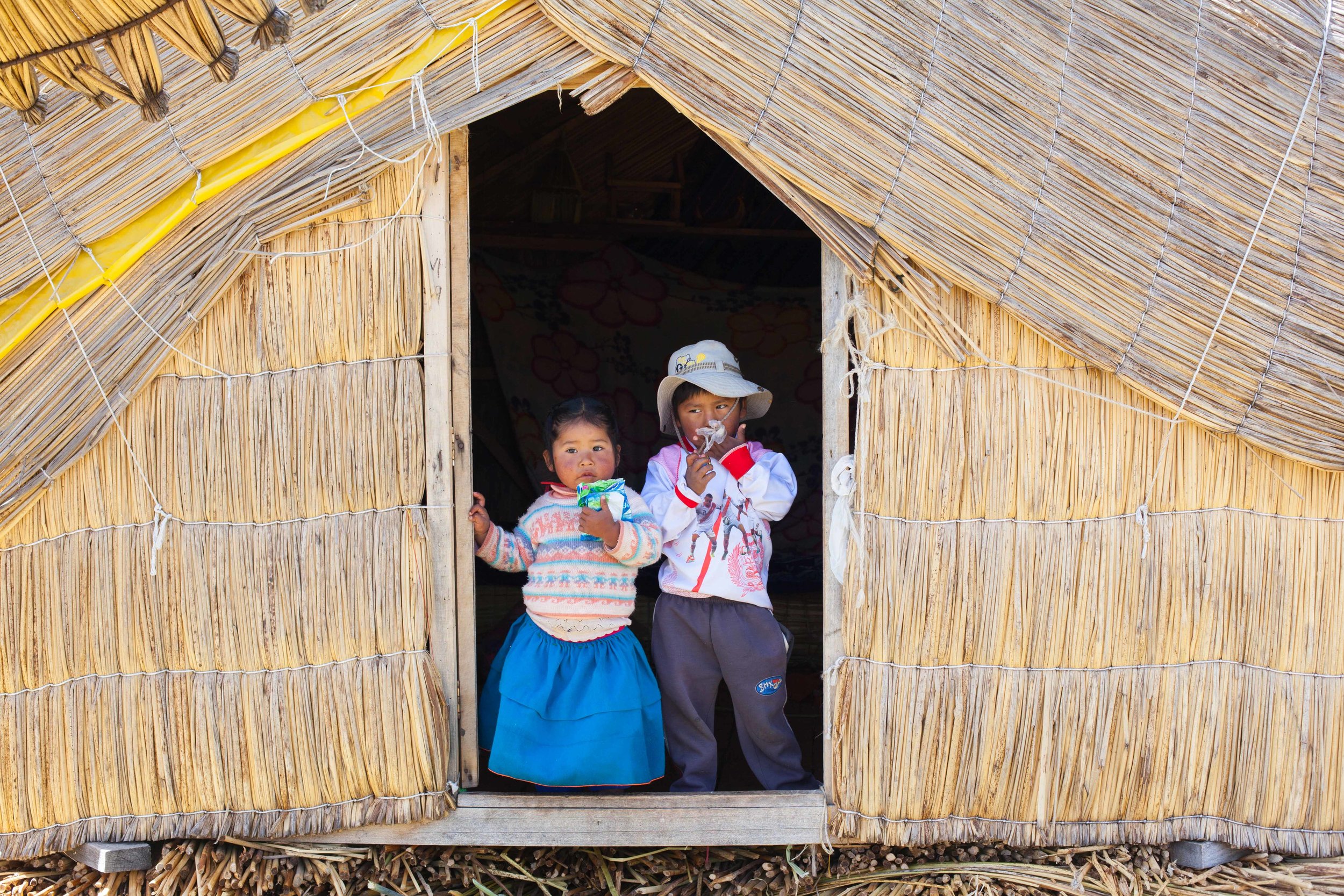 Children living in a reed hut on a island made of reed in Peru.
