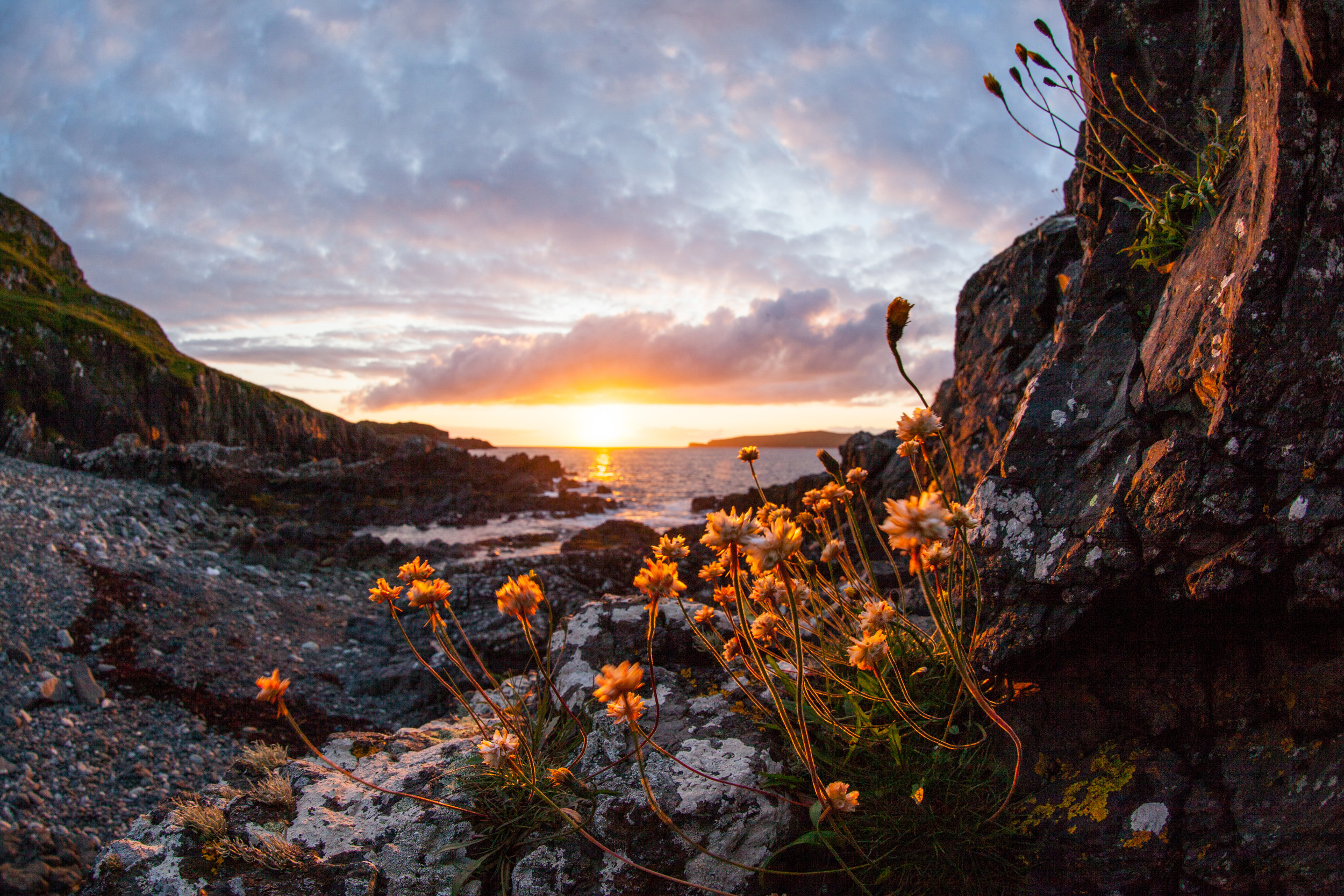 A beautiful fish eye style of the sun setting over a beach in Scotland.