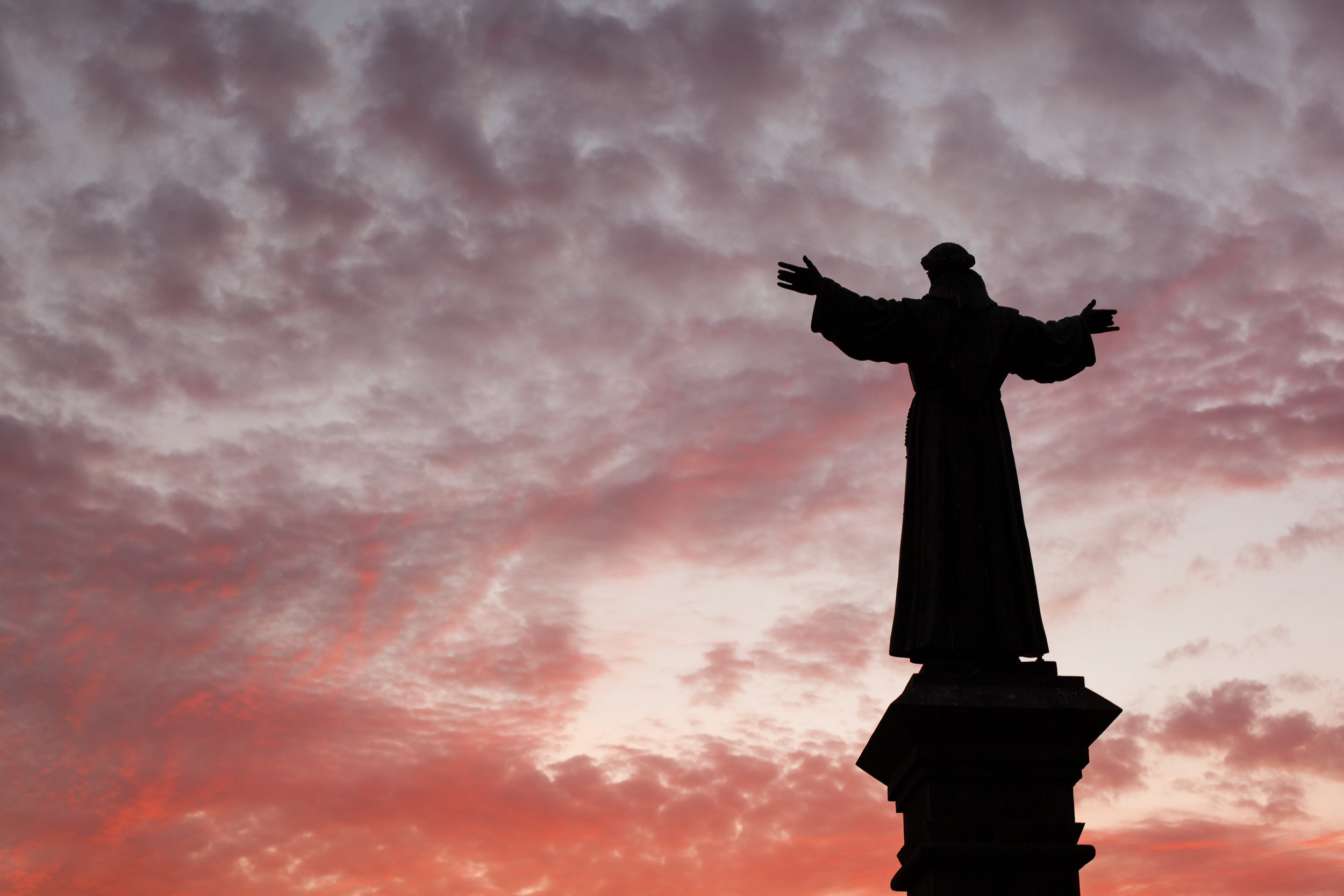 A blood red sky behind a religious statue in Arequipa, Peru.