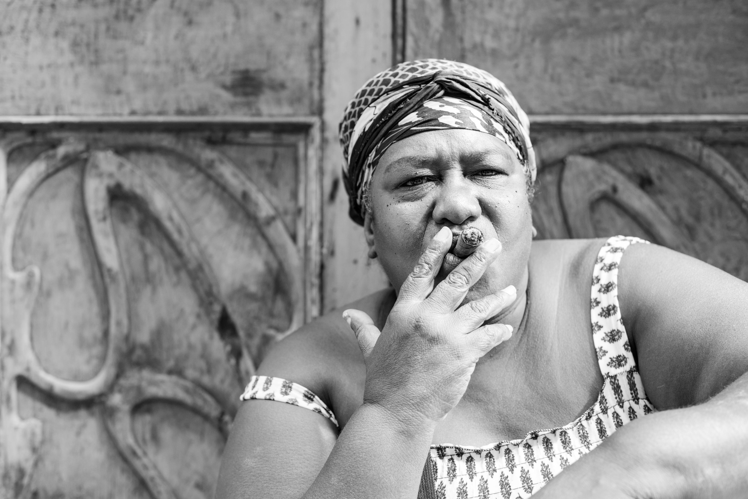A black and white portrait of a curvy Cuban lady smoking a cigar.
