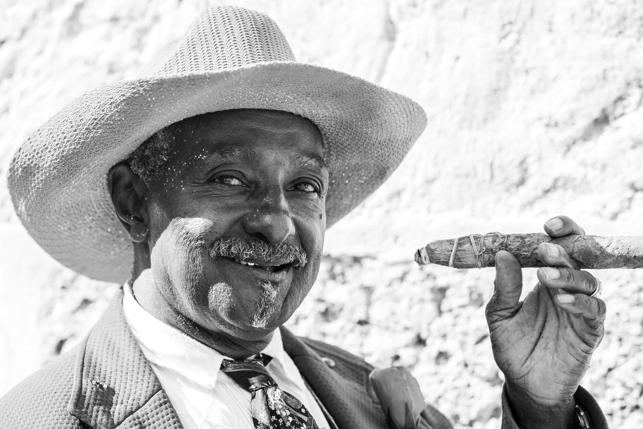 A black and white street portrait of a friendly man smoking a cigar in La Habana.