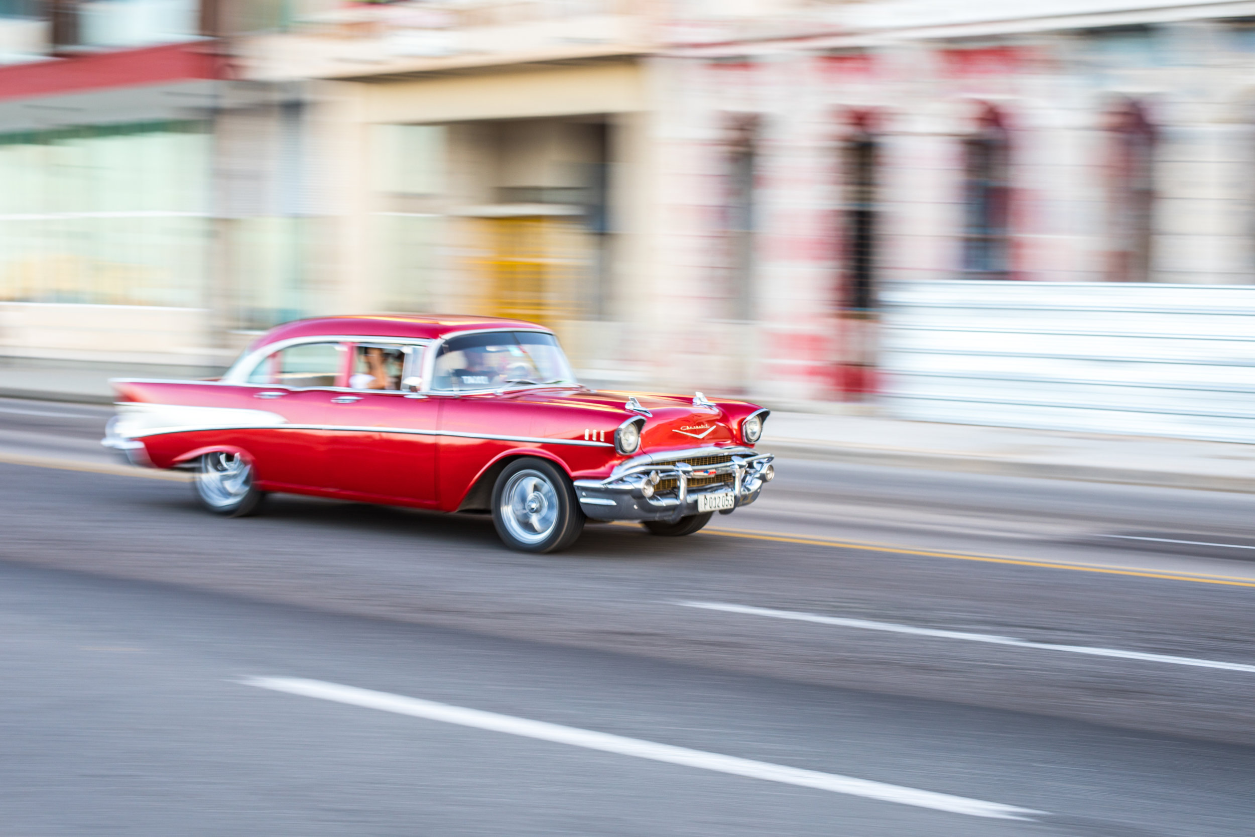 A  1957 red four door Chevrolet drives along the malecon in Havana, Cuba.