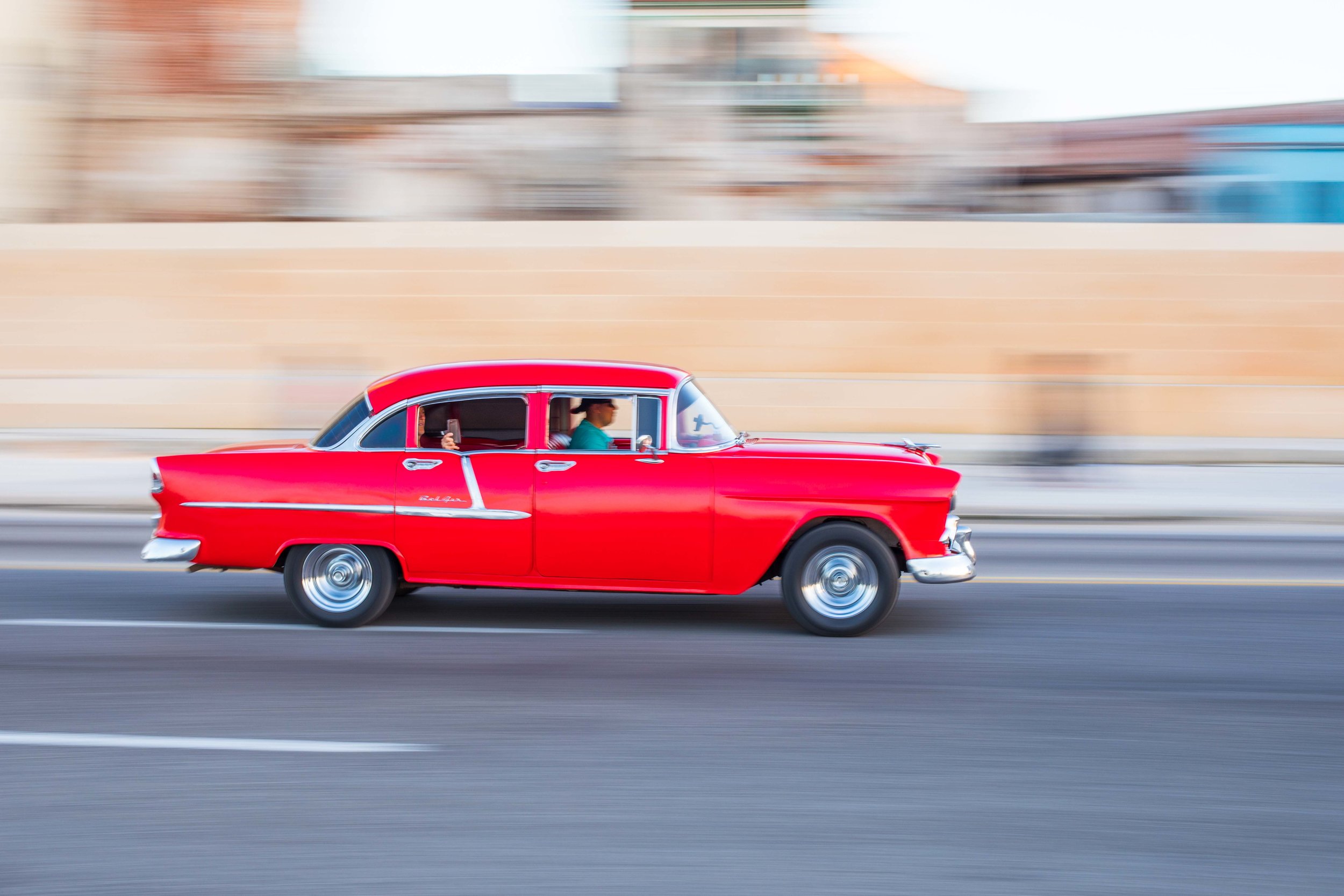 A beautiful red 55 chevy classic car drives along the malecon in Havana, Cuba.