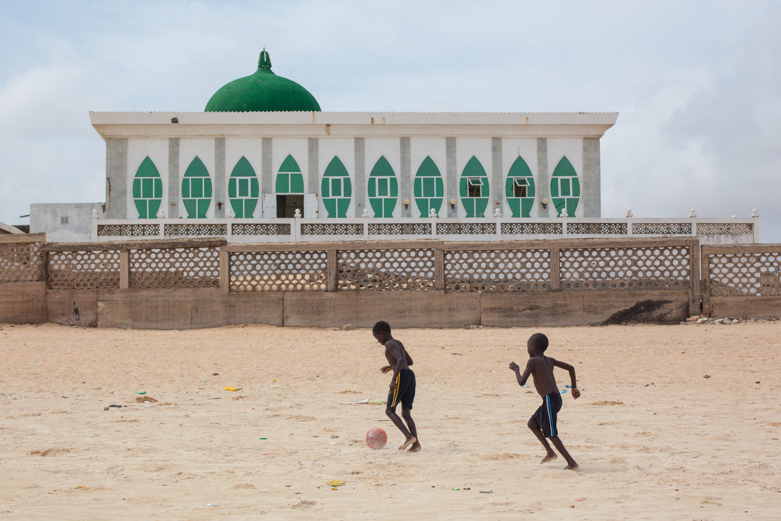 Boys playing football on a beach in Dakar in front of the Grande Mosquée de Yoff.