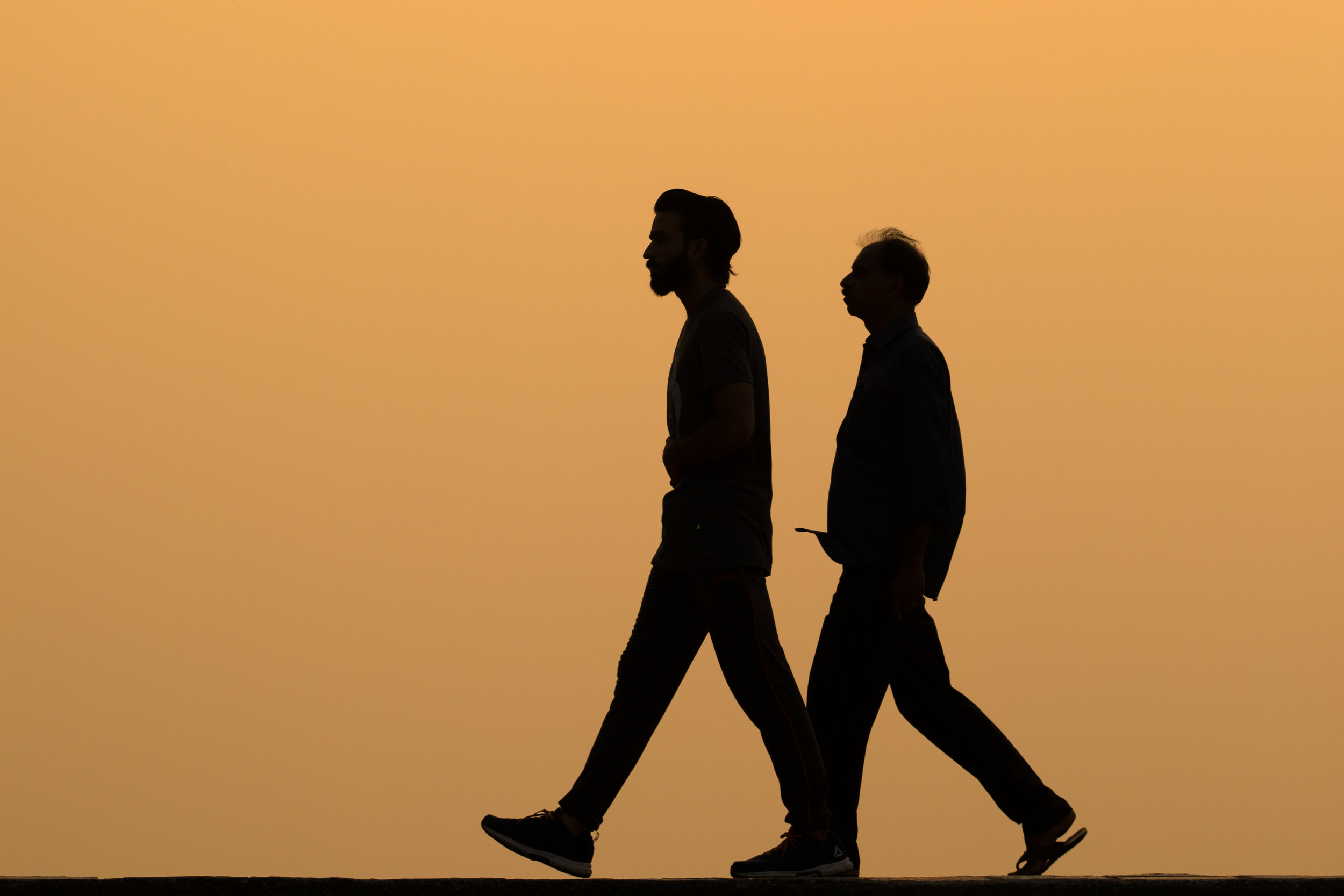 Silhouetted walkers at Sunset in Kochi, India.