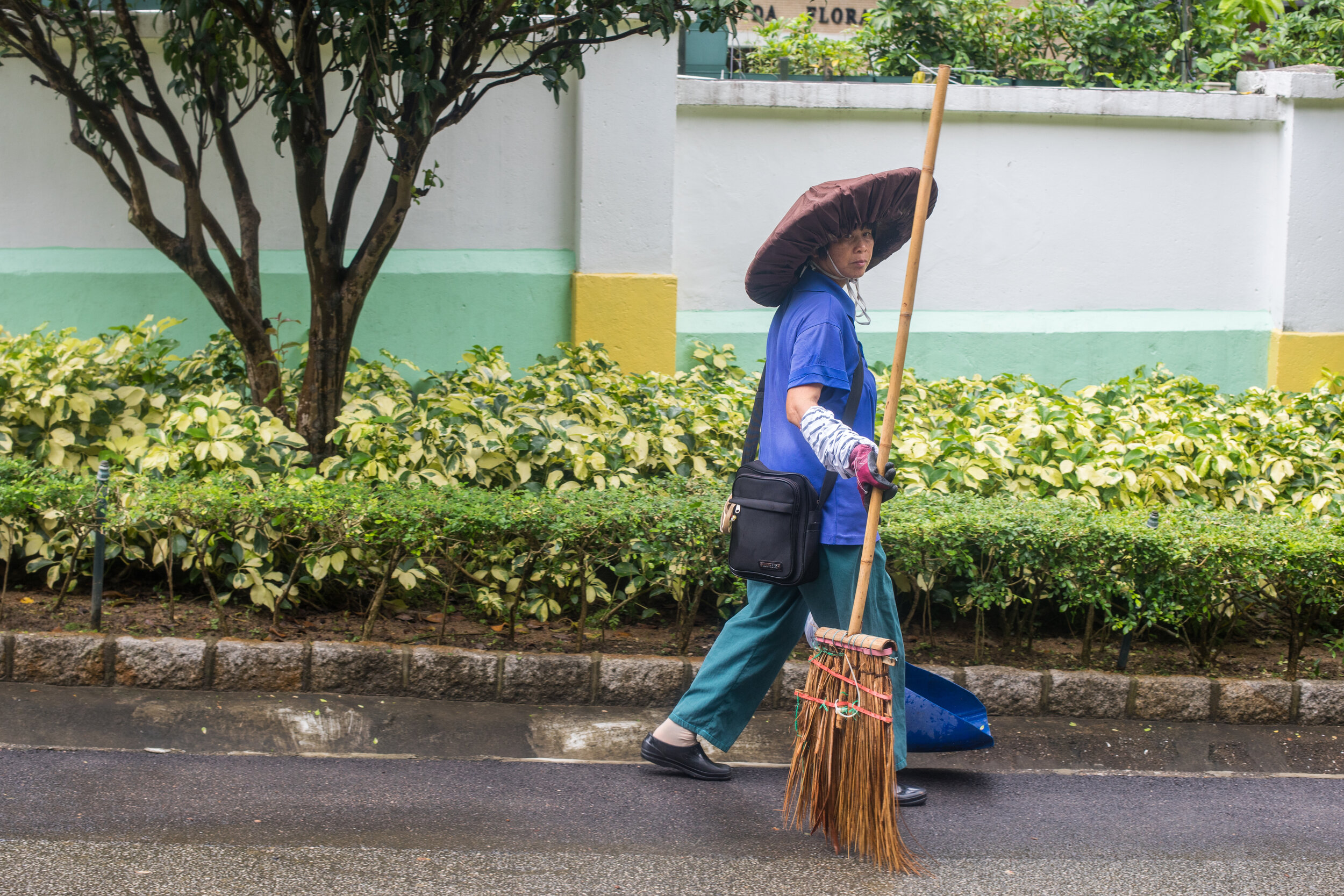 Candid street portrait, a street cleaner wears the traditional Macanese Hat. 