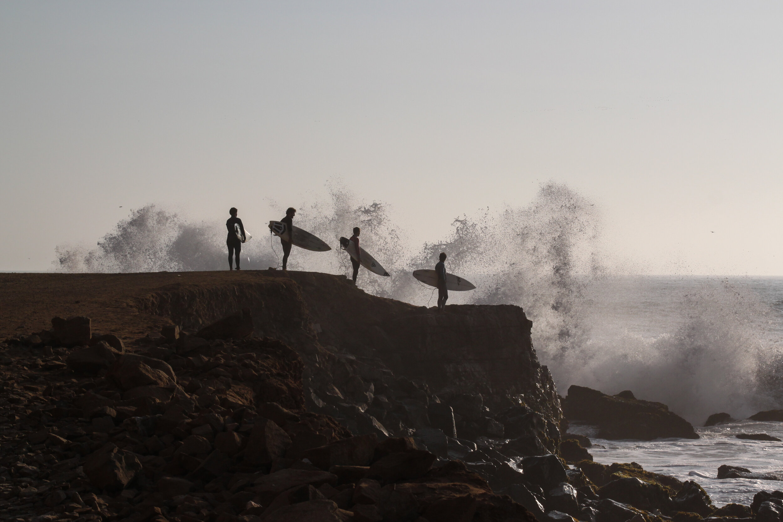 Four surfers waiting to enter the Ocean in Lima, Peru.