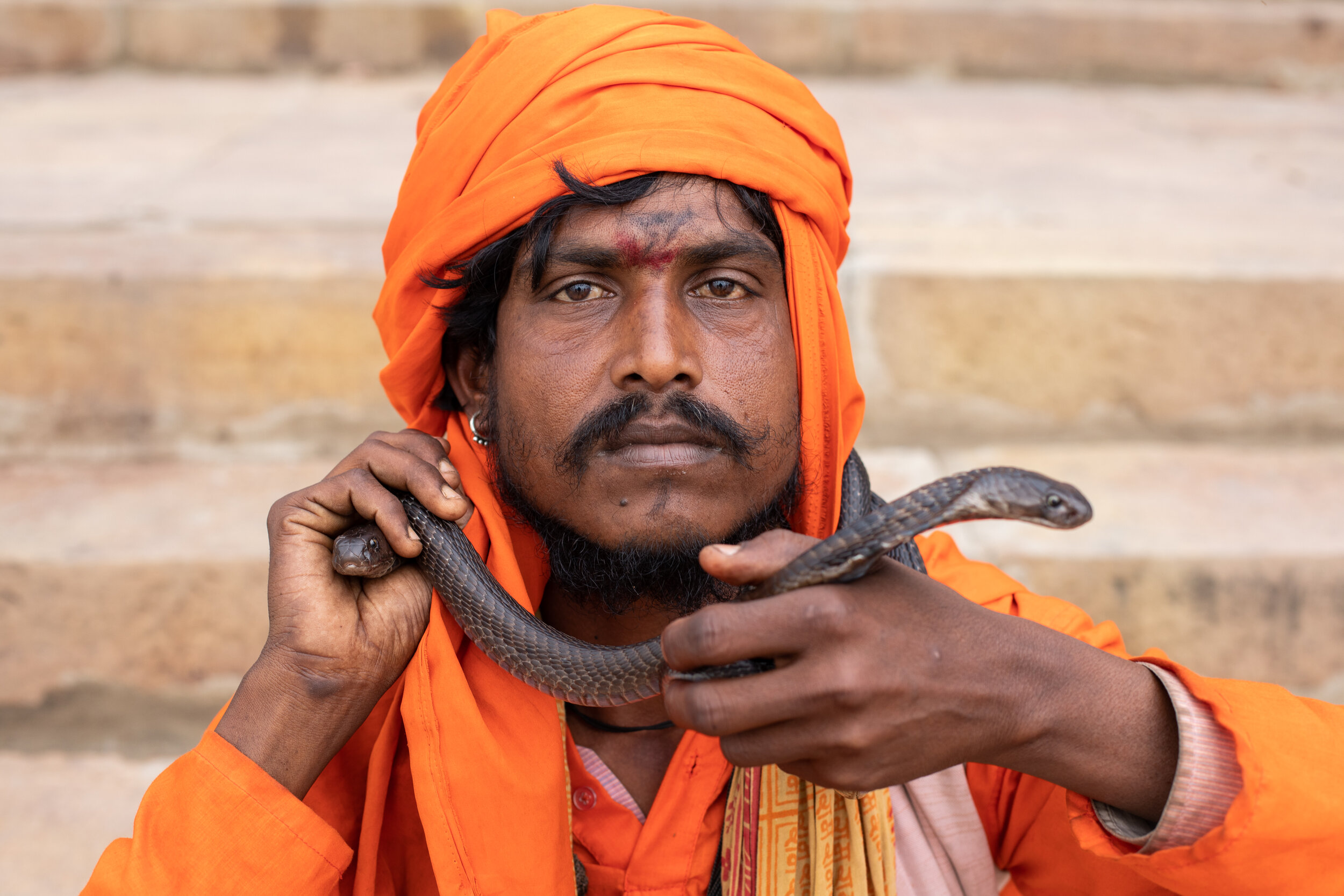 An Indian snake charmer performs on the stairs above the Ganges in Varanasi.