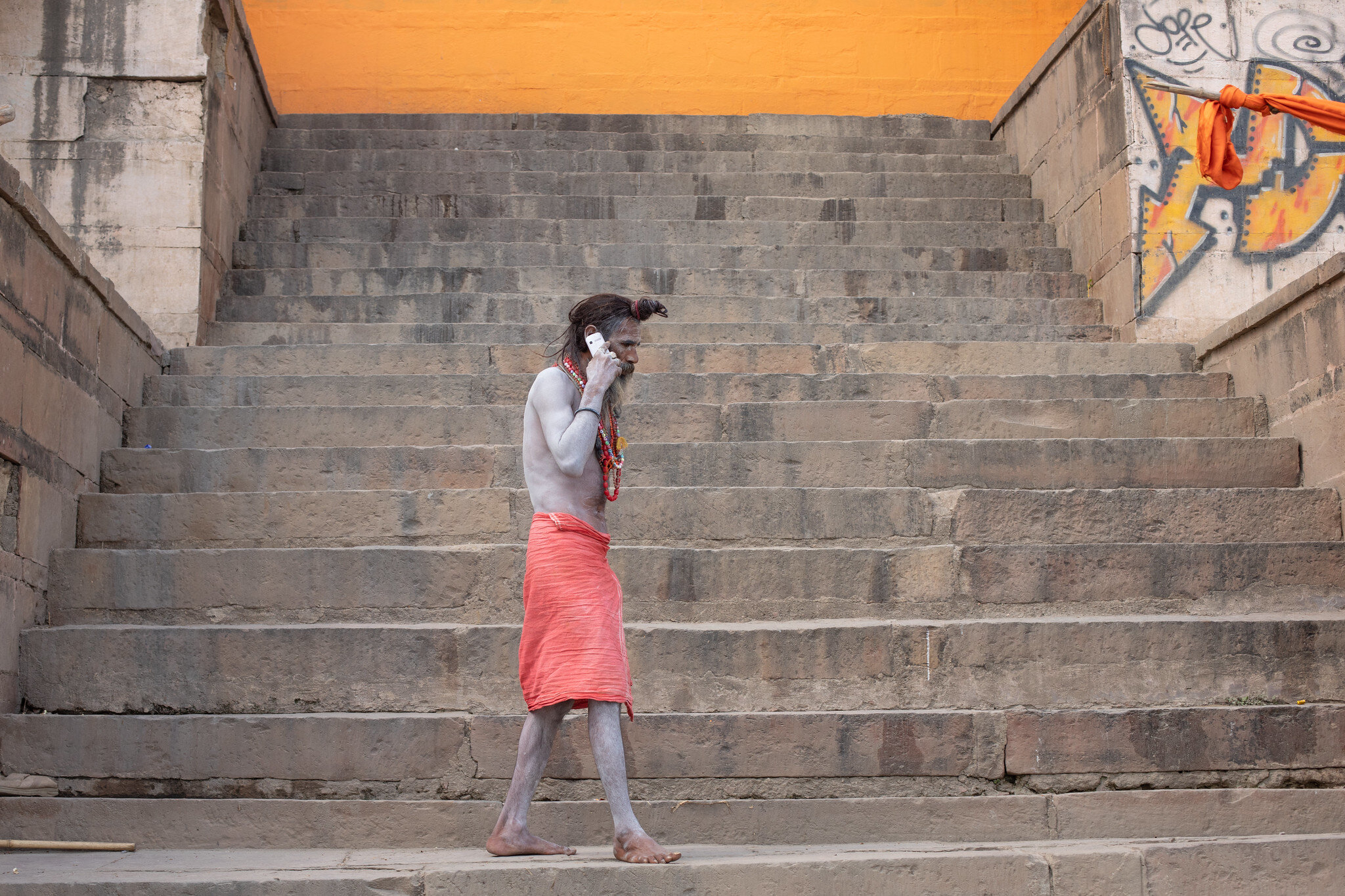 An amusing candid street photograph of a Holy Man speaking on a mobile phone in Varanasi, India.