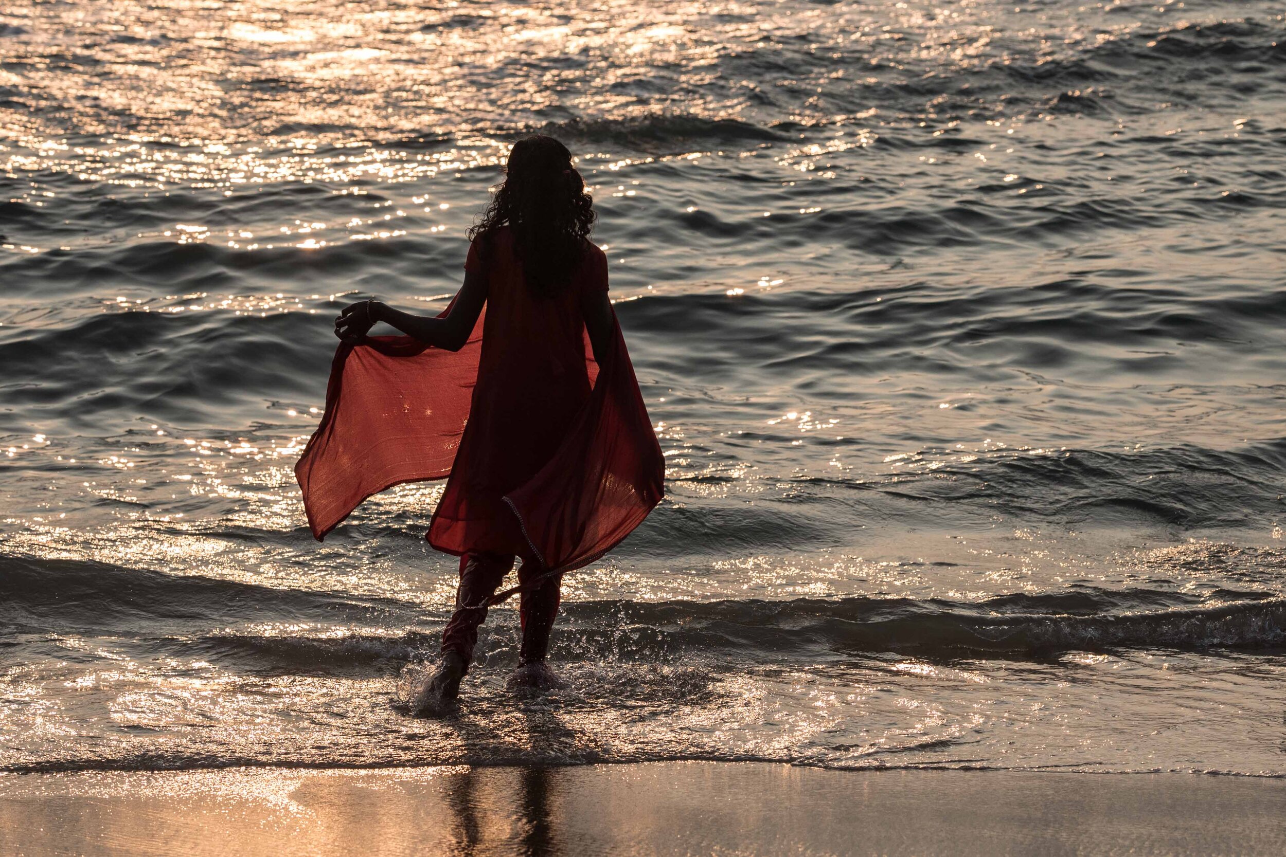 An Indian girl looks out to the ocean at the end of the day on the beach in Varkala.