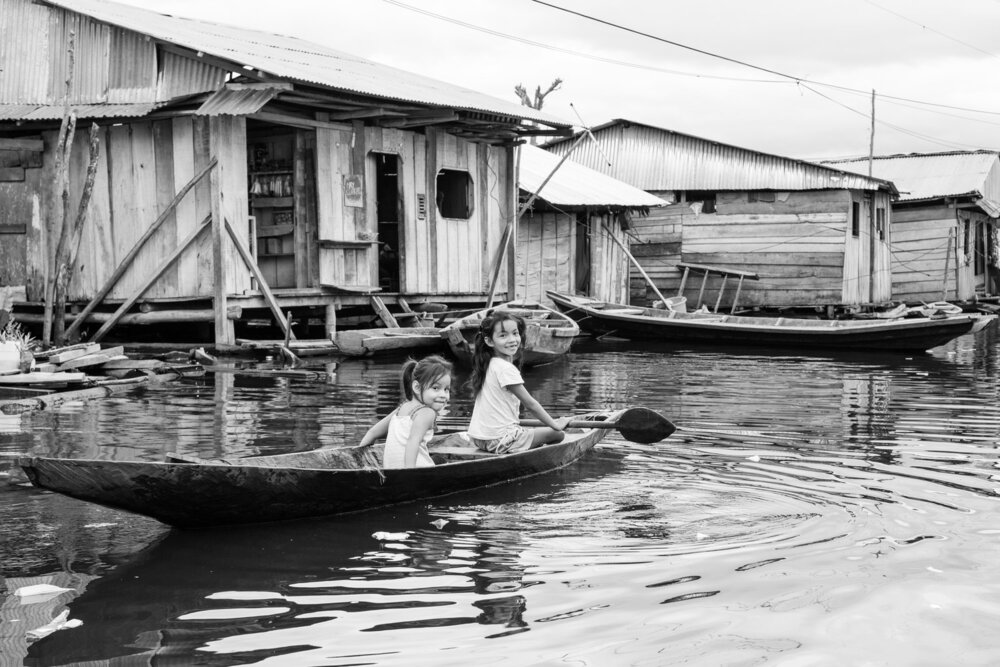 Dos niñas dirigen una canoa a través de la villa inundada de Belén, Iquitos, Perú.