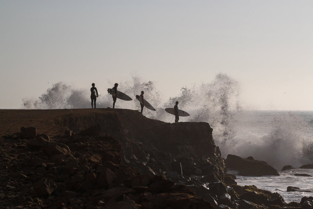 Surfistas formados para entrar al mar durante la marea alta en La Herradura, Lima, Perú.