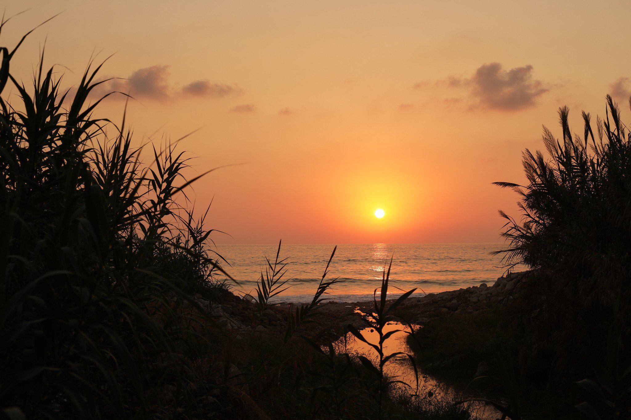 A small river runs into the Mediterranean Sea as the sun sets in Jbeil, Lebanon.