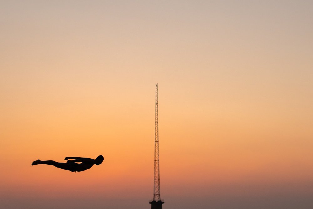 A local dives off the Beirut Corniche into the Sea at sunset.