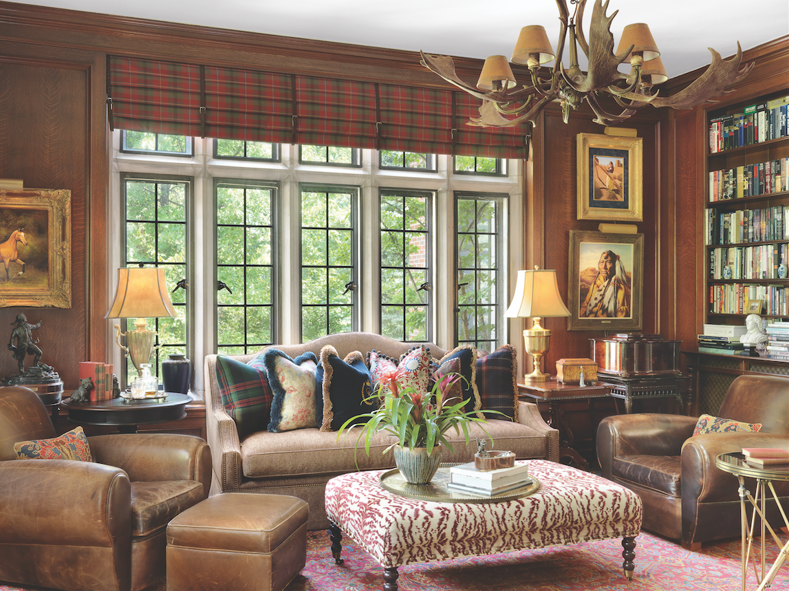 Leather and plaid bring traditional style to the wood-paneled library, awash in light from a wall of clerestory over casement windows. 