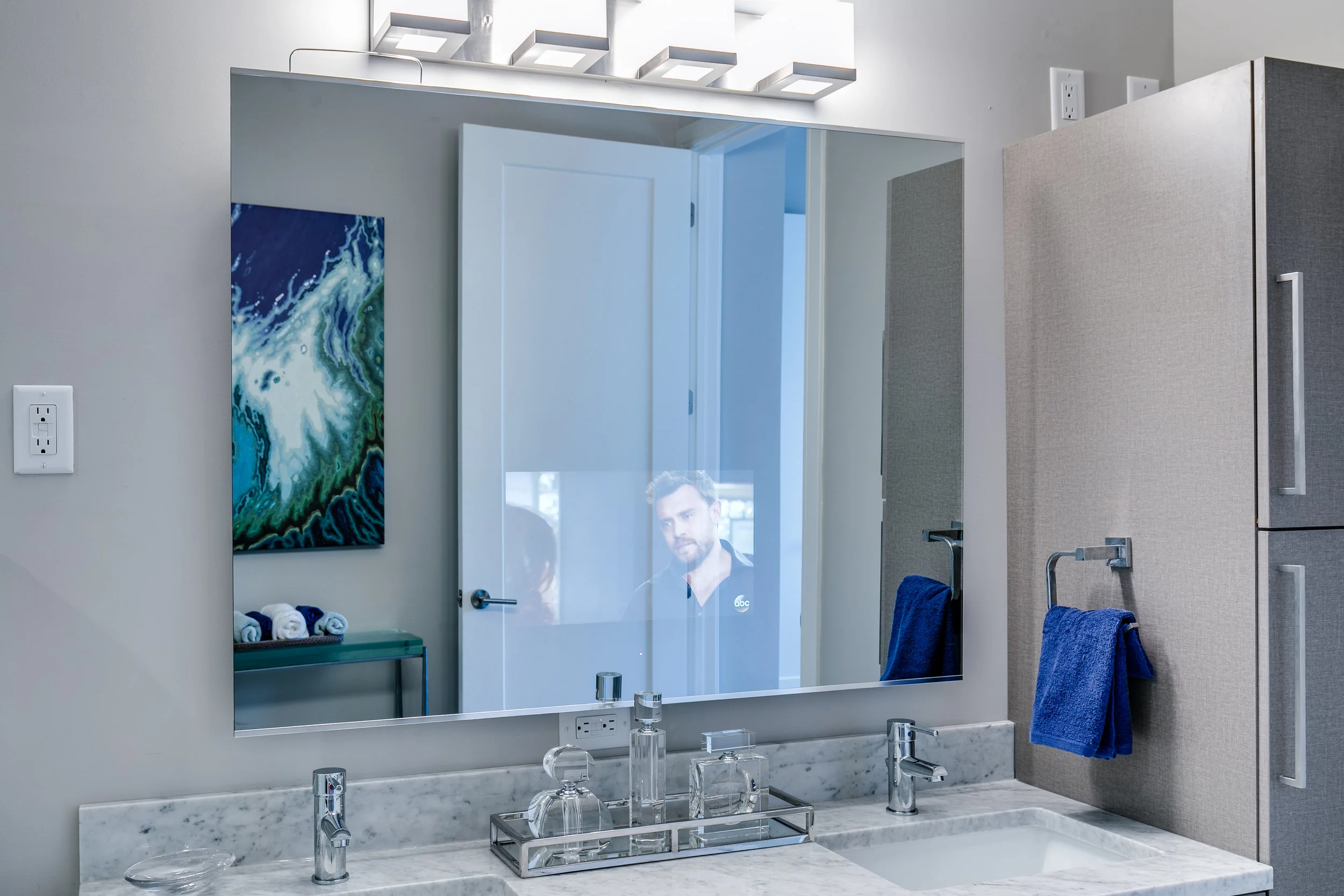 A TV inside the master bathroom mirror in a unit at The Barton.