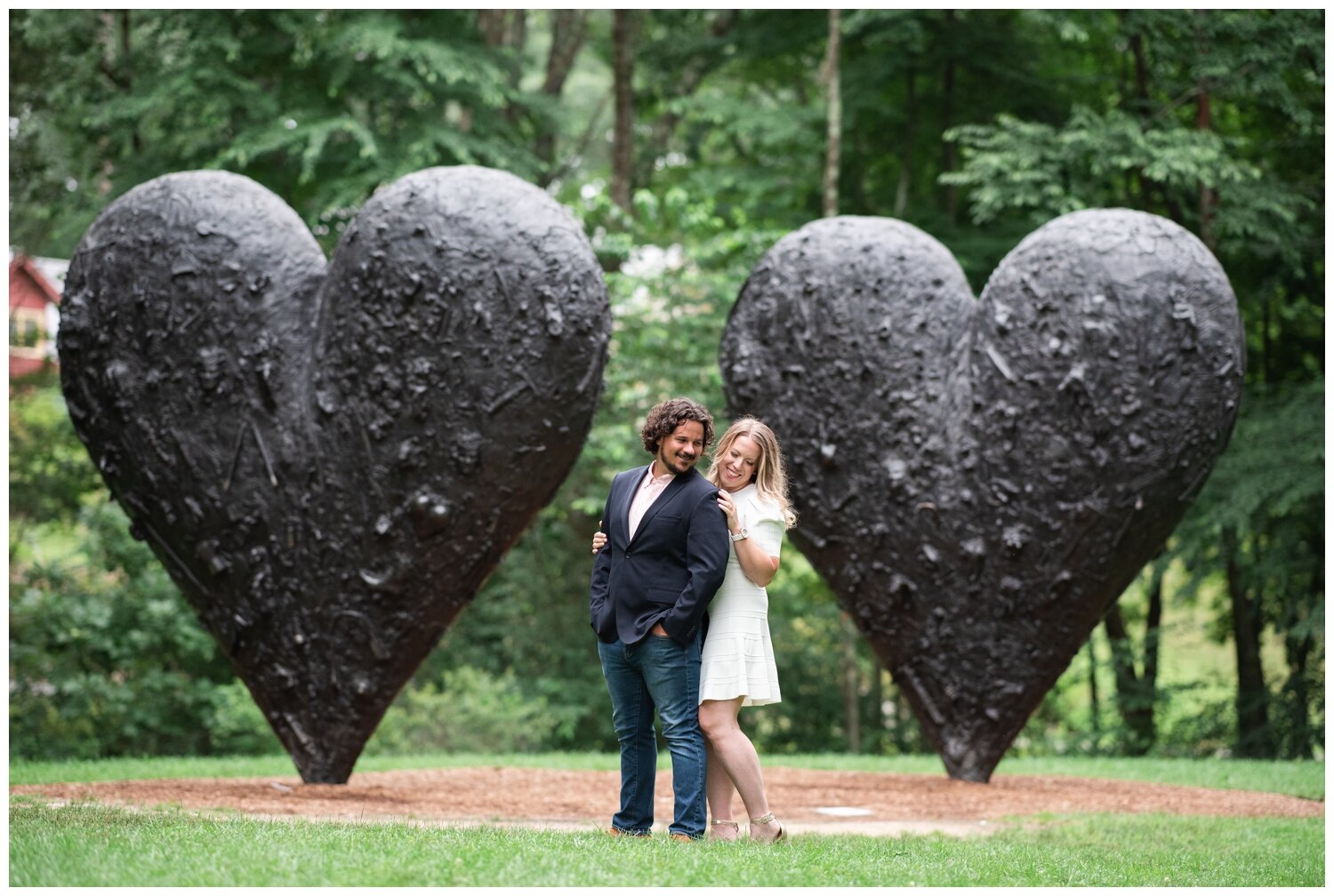 heart sculpture with engaged couple standing in front