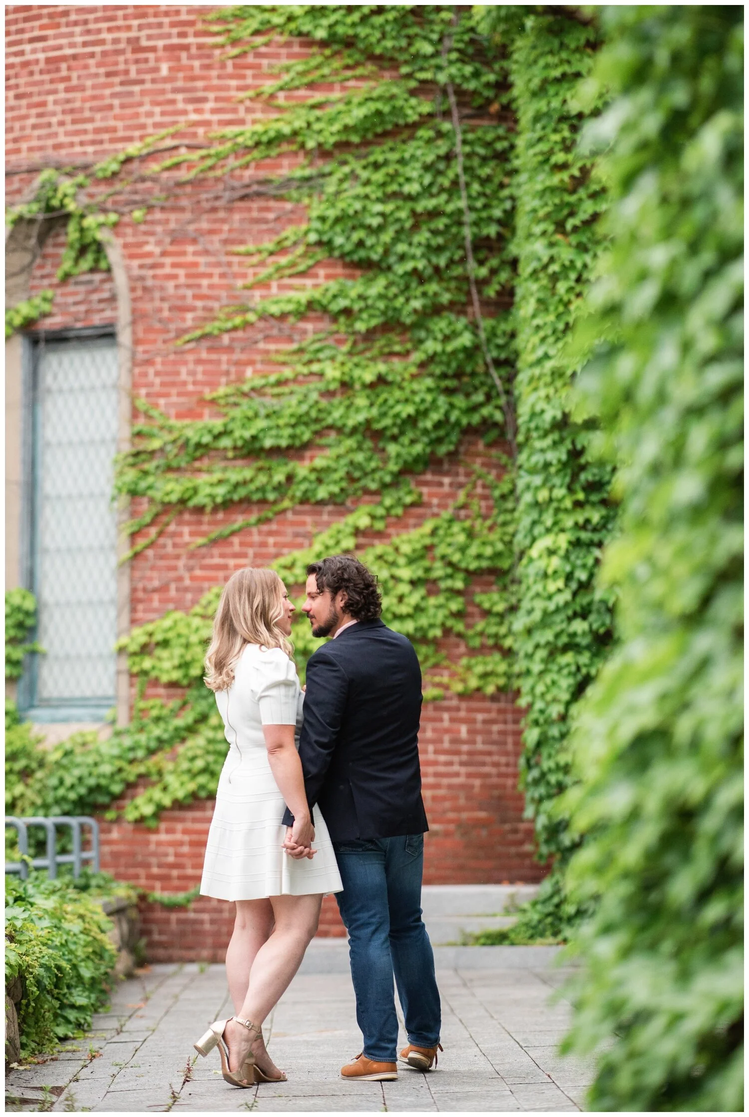 engaged couple kissing in front of ivy wall at deCordova Sculpture Park
