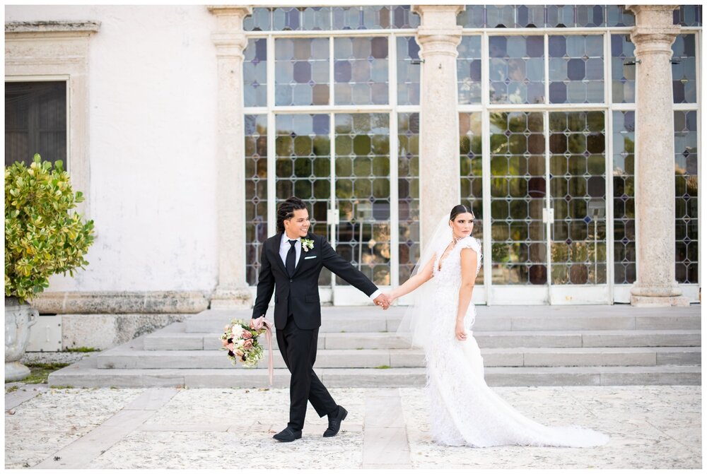 bride and groom walking in front of window at Vizcaya Museum and Gardens