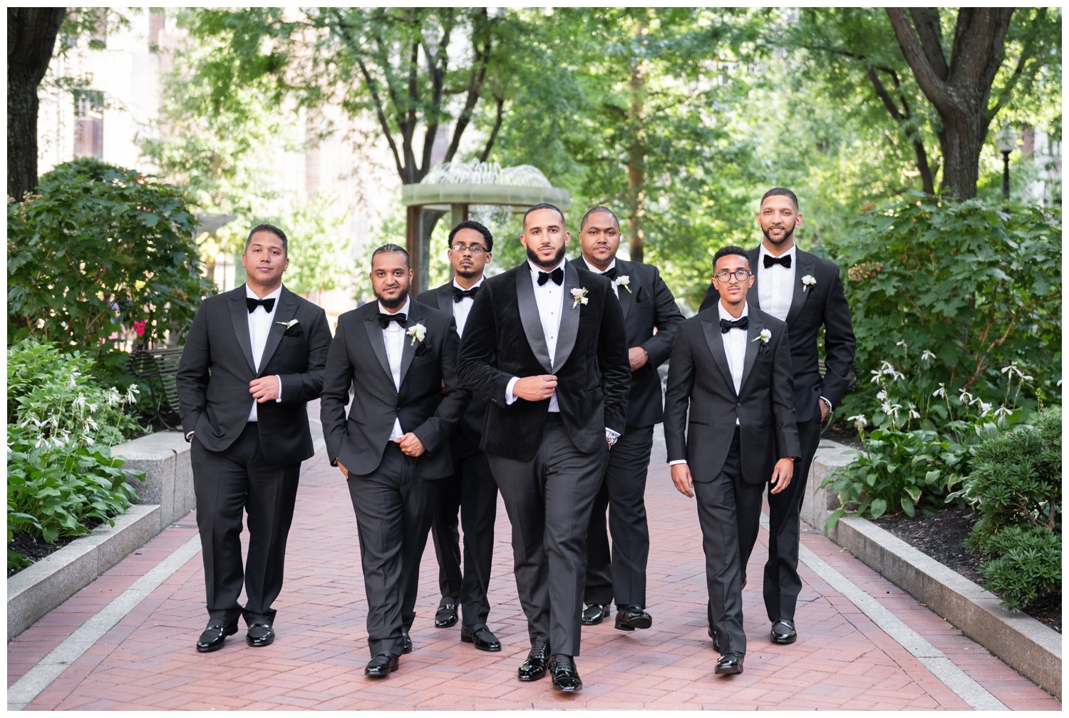 groom and groomsmen walking outdoors in black tuxedos at Post Square Office
