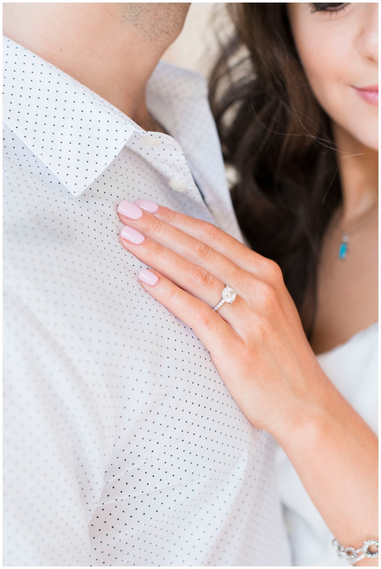 bride's hand with wedding ring touching the grooms chest