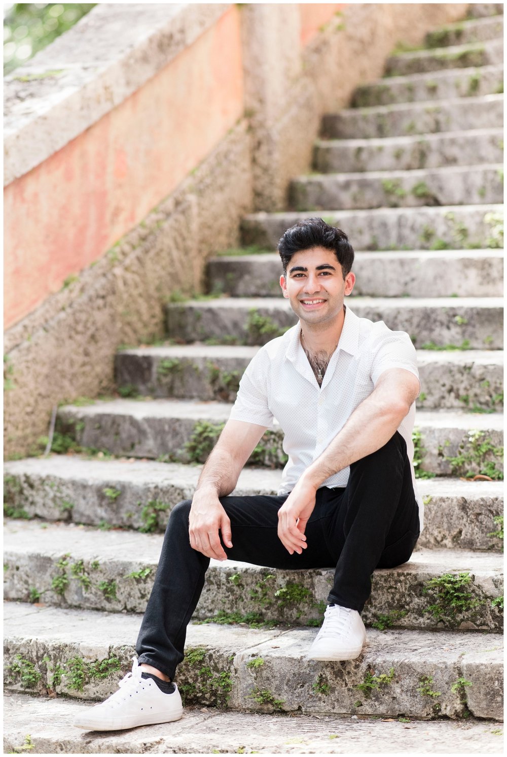 guy sitting on stairs in white shirt and black pants for Miami engagement photographer
