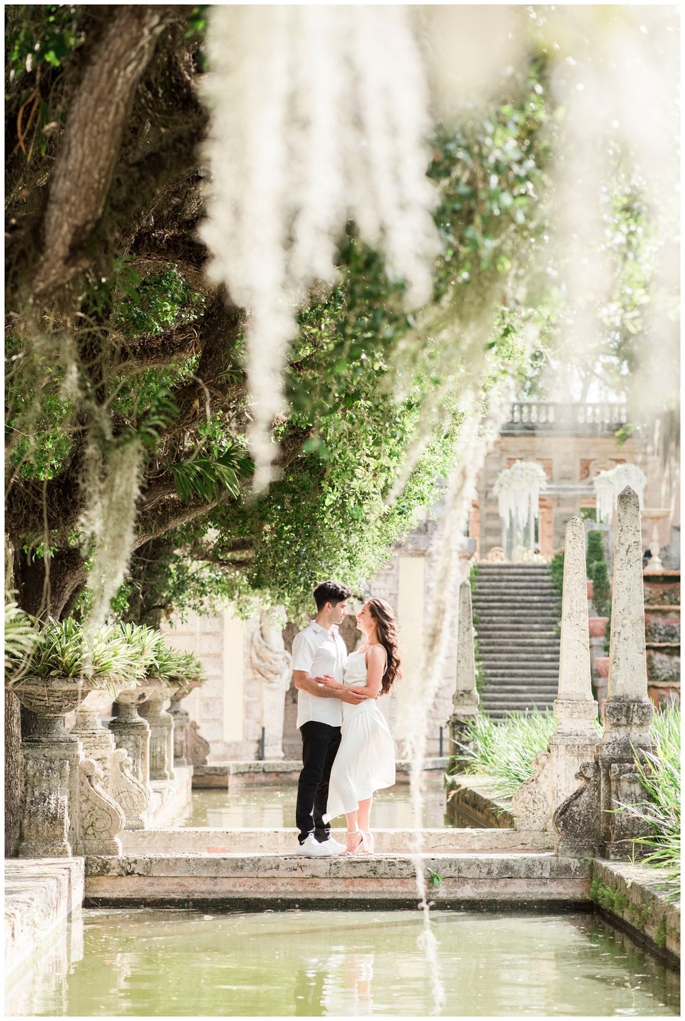 engaged couple standing and posing under mossy trees at Vizcaya Museum engagement photos