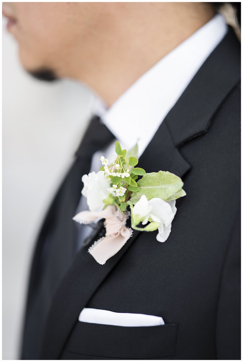 close up of boutonniere on black suit of groom