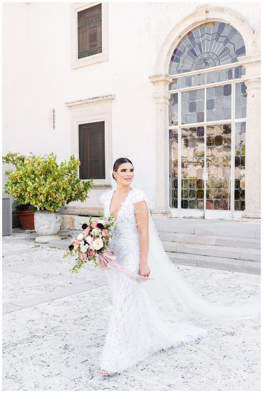 bride standing in front of window outside Vizcaya Museum and Gardens Miami wedding photographer
