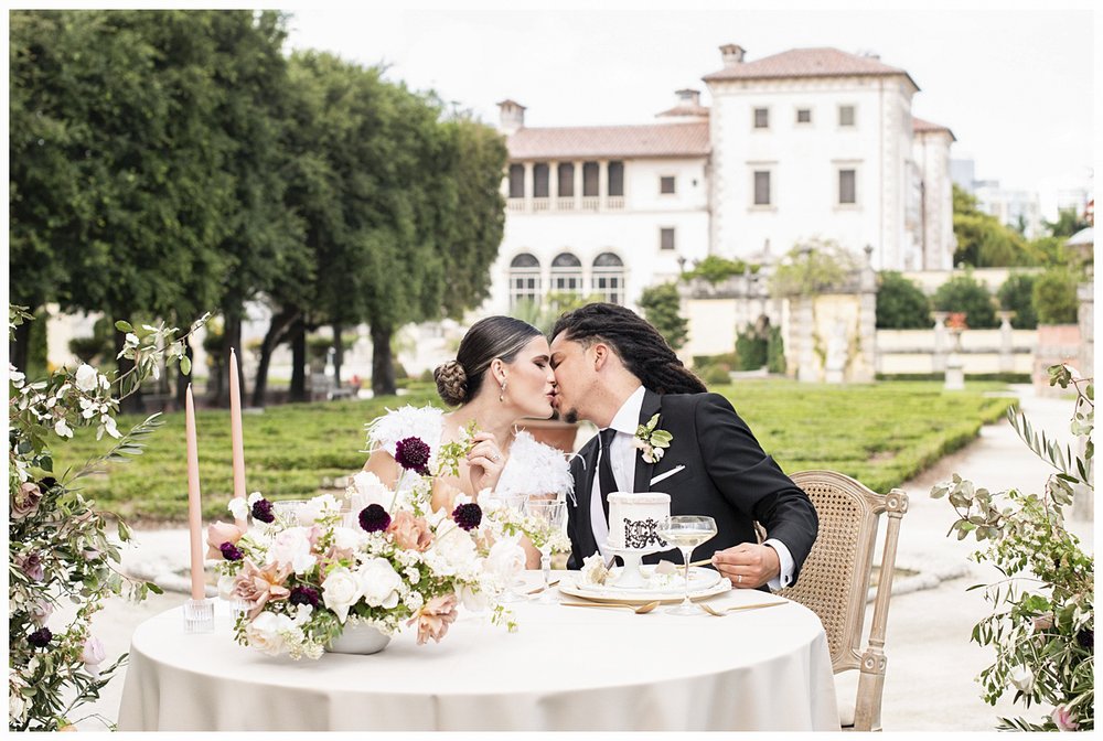 newlyweds kissing at sweetheart table at elopement reception editorial by Miami wedding photographer