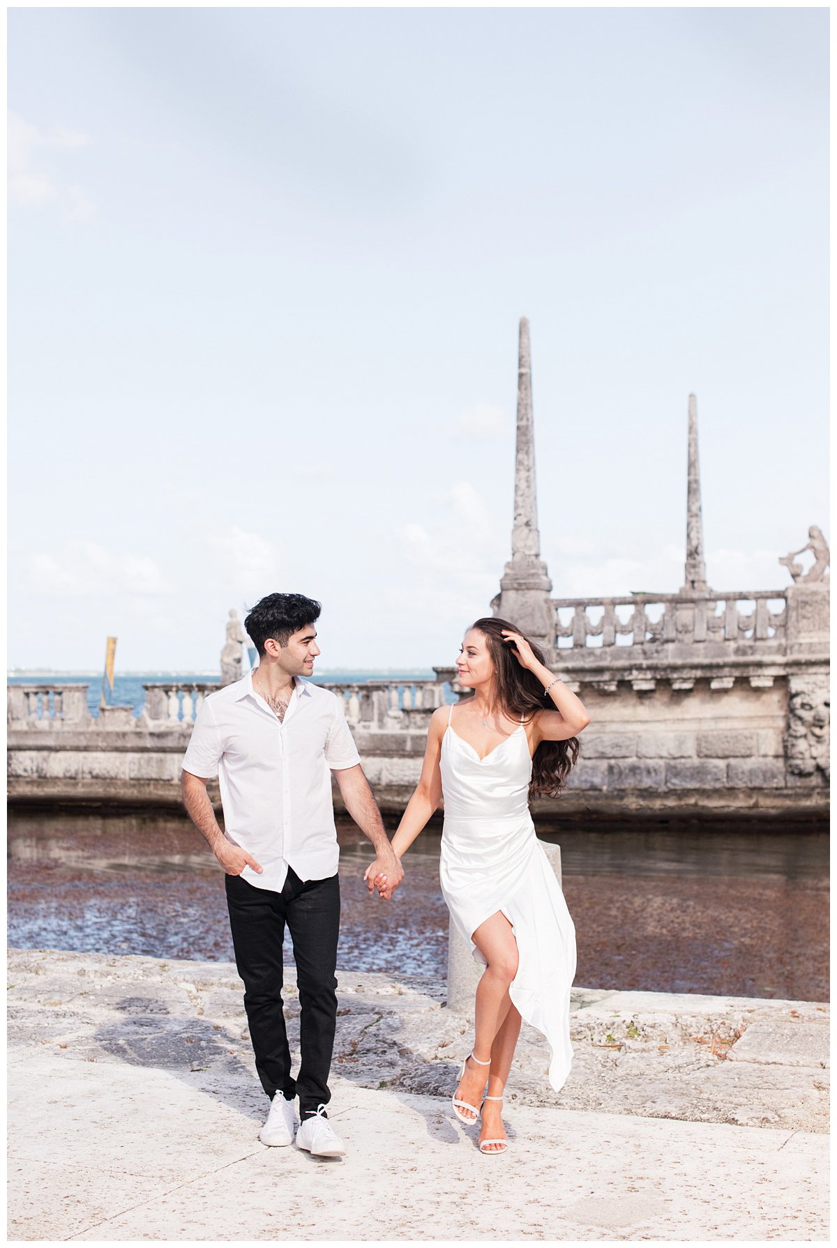 engaged couple holding hands and walking by a waterfront in Miami, Florida