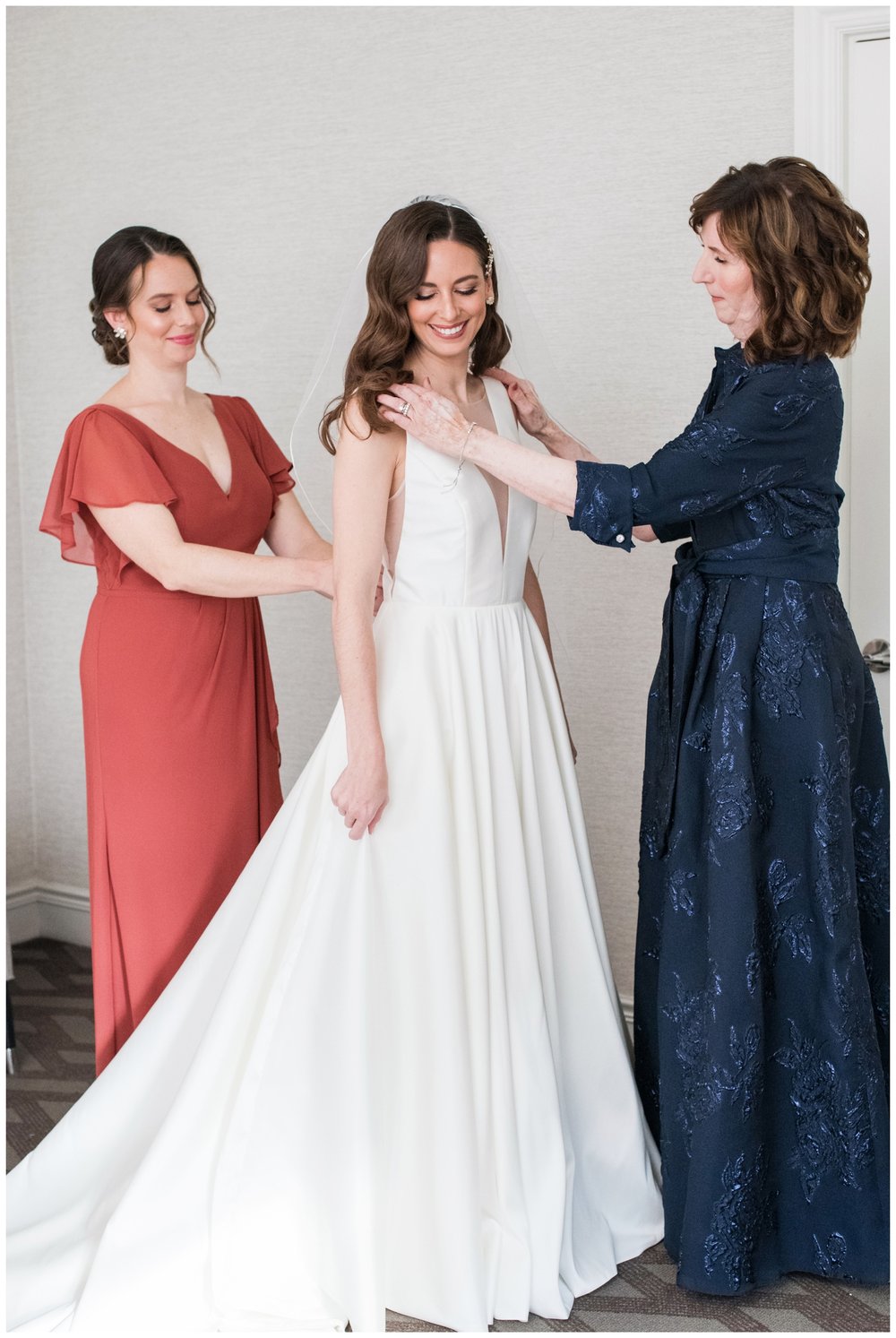 bride getting ready with mom fastening gown