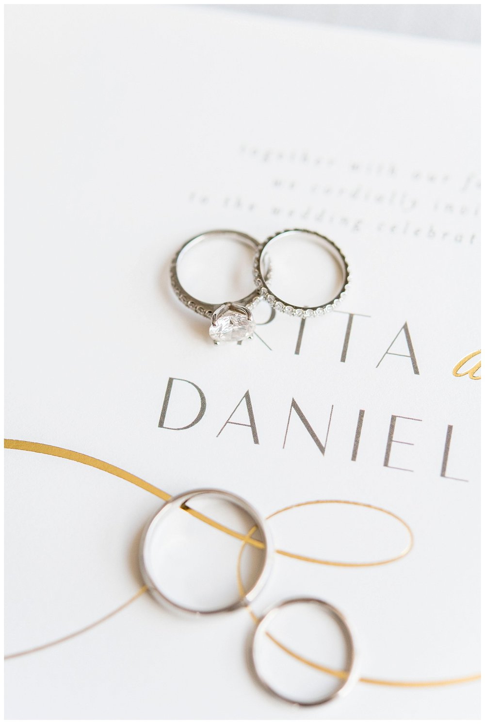 wedding rings laying on white invitation suite