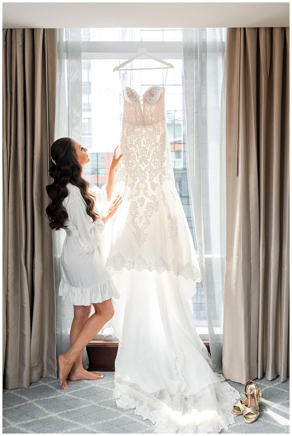 white wedding gown hanging with bride touching in